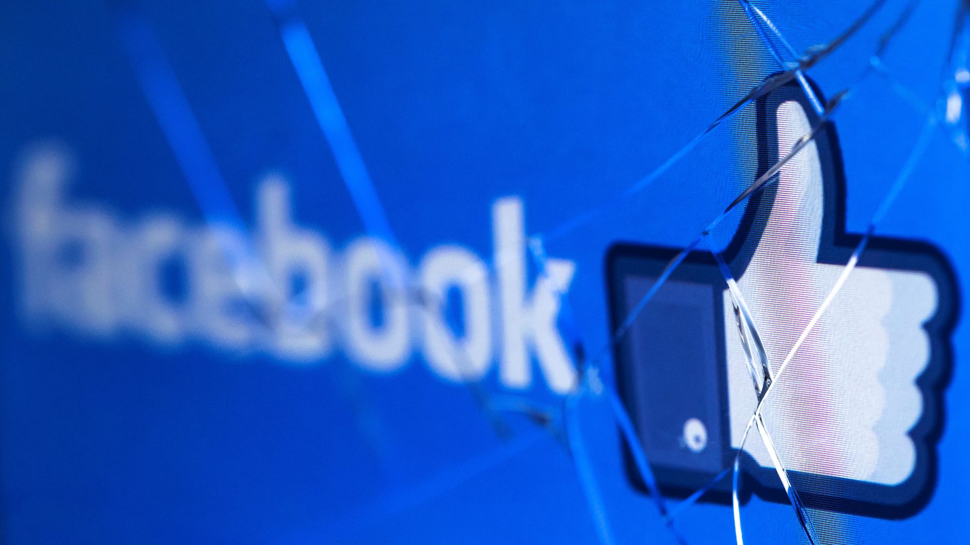 Facebook logo and "like" thumbs up icon on a cracked phone screen