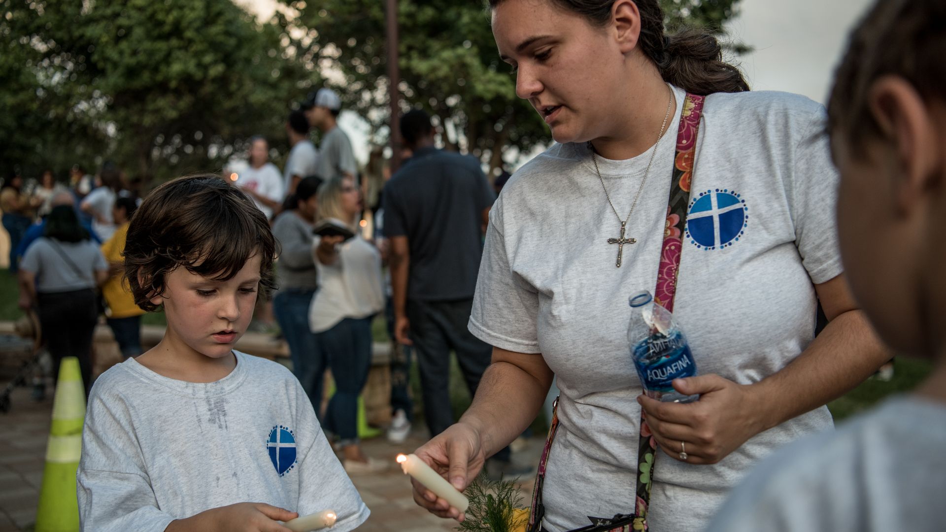 Katelyn Cooper, 26, and her two sons Trevor, 5, and Bronston, 7, light candles at the end of the prayer vigil at the University of Texas of the Permian Basin