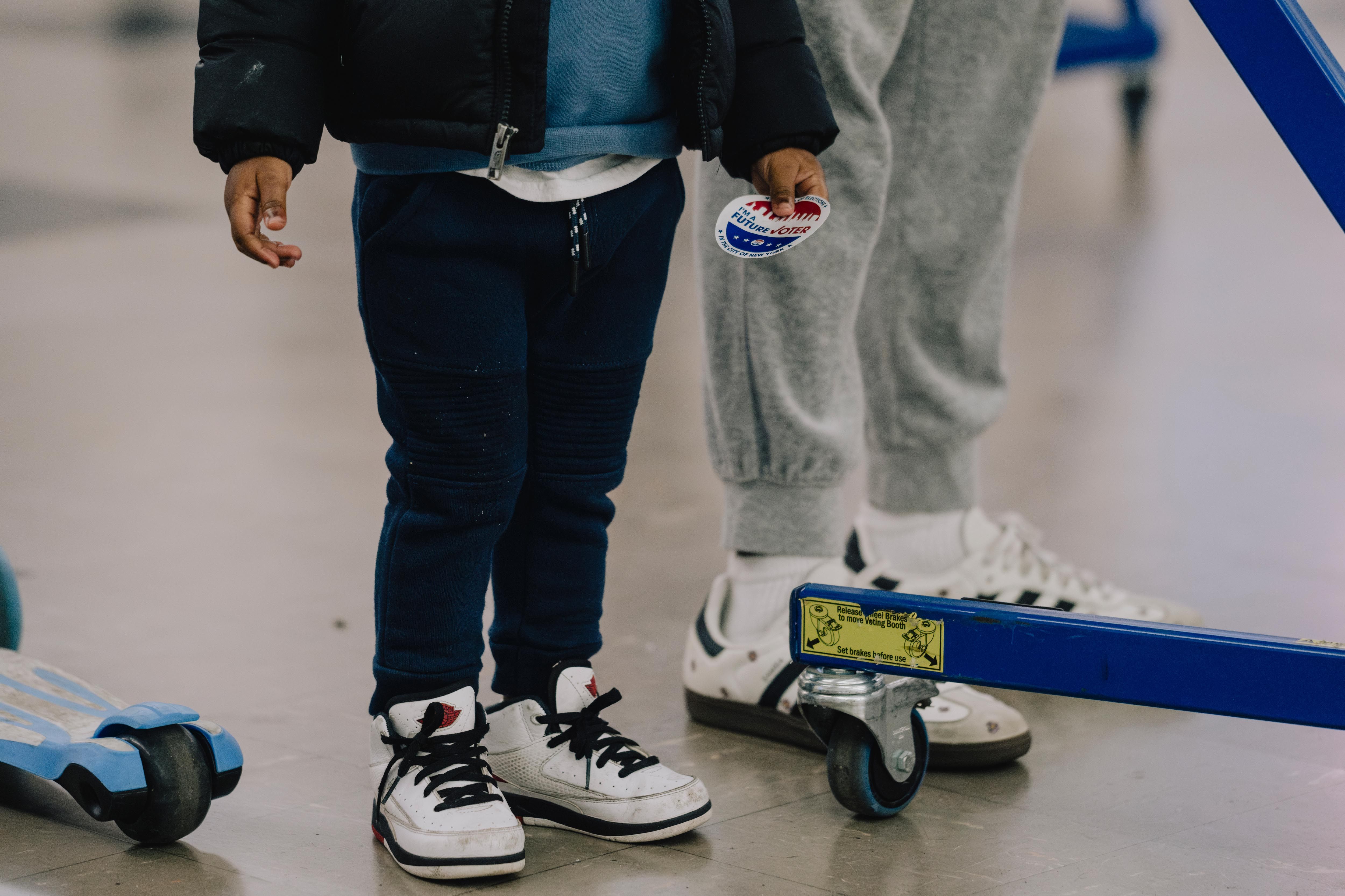 A young child holds an "I'm a future voter" sticker. 