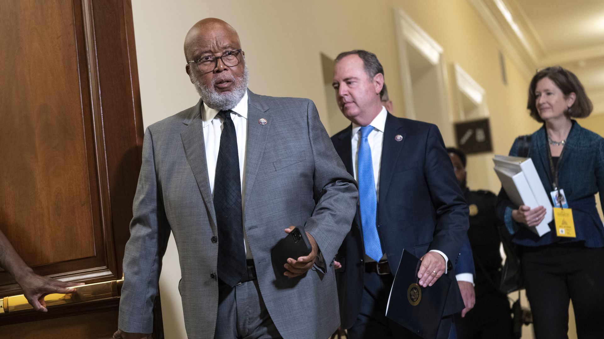 Rep. Bennie Thompson, wearing a gray suit, white shirt and dark blue tie, and Adam Schiff, wearing a dark blue suit jacket, white shirt and light blue tie, walking in a House office building hallway.