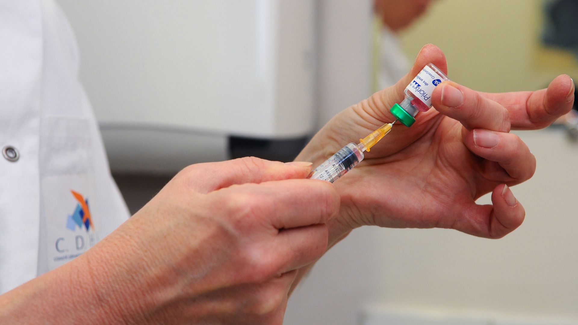 In this image, a doctor or nurse prepares a shot. 