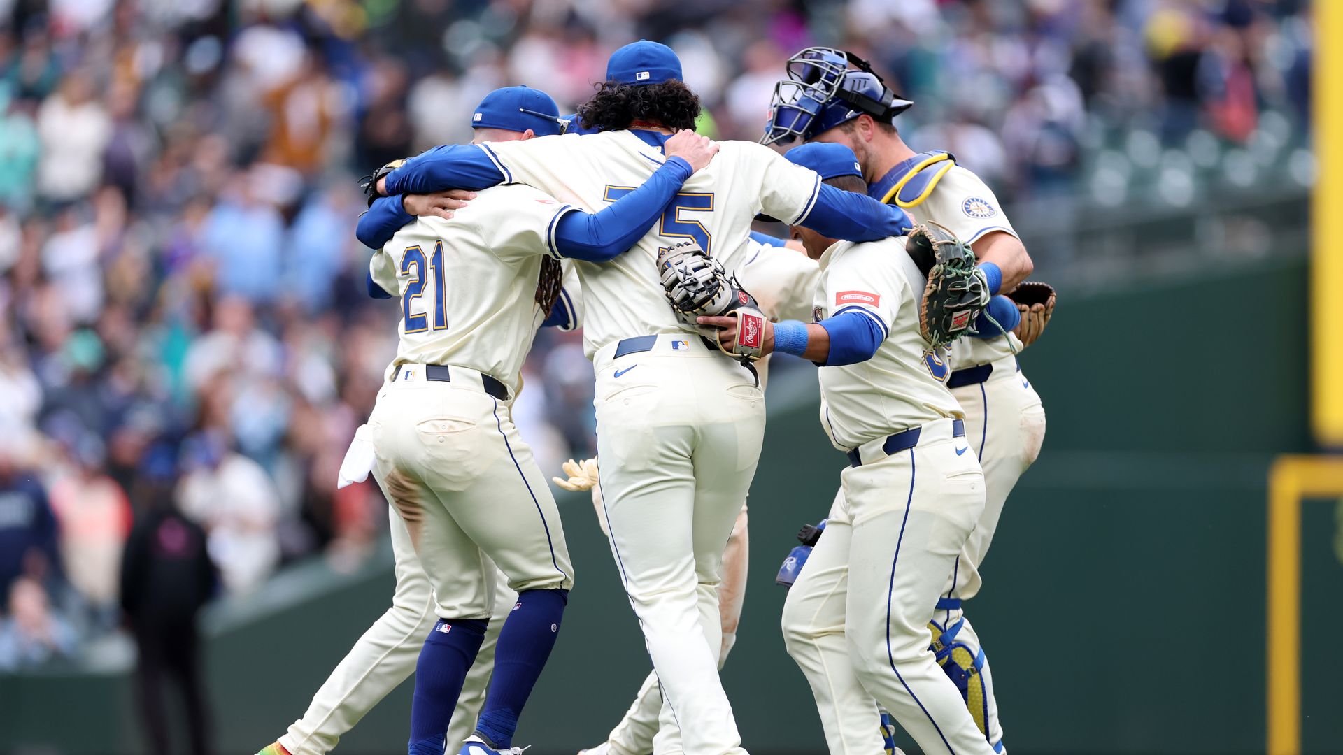 A group of baseball players celebrate in a circle with their arms around each other. 
