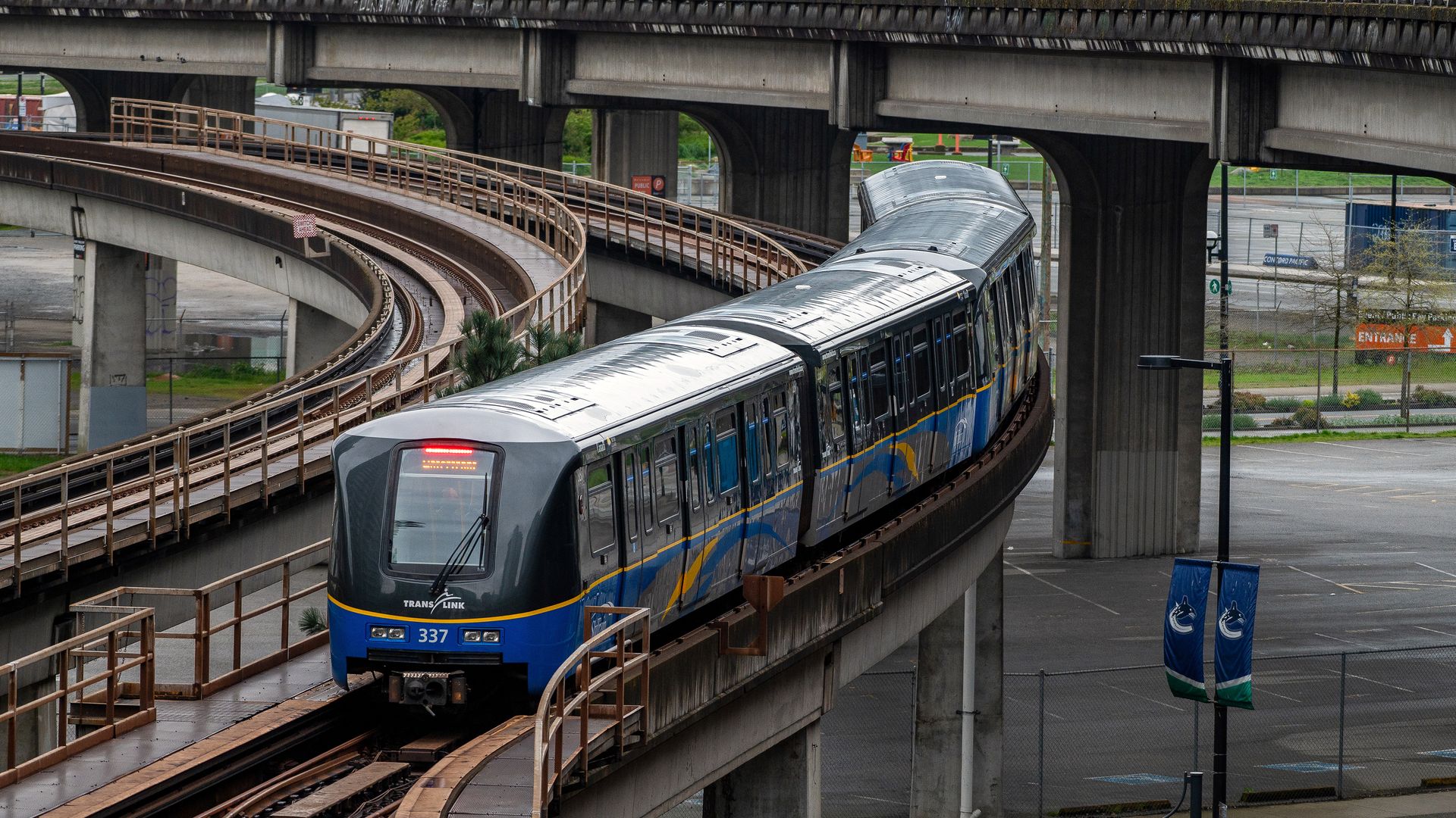 A silver and blue light rail train on an elevated track. 