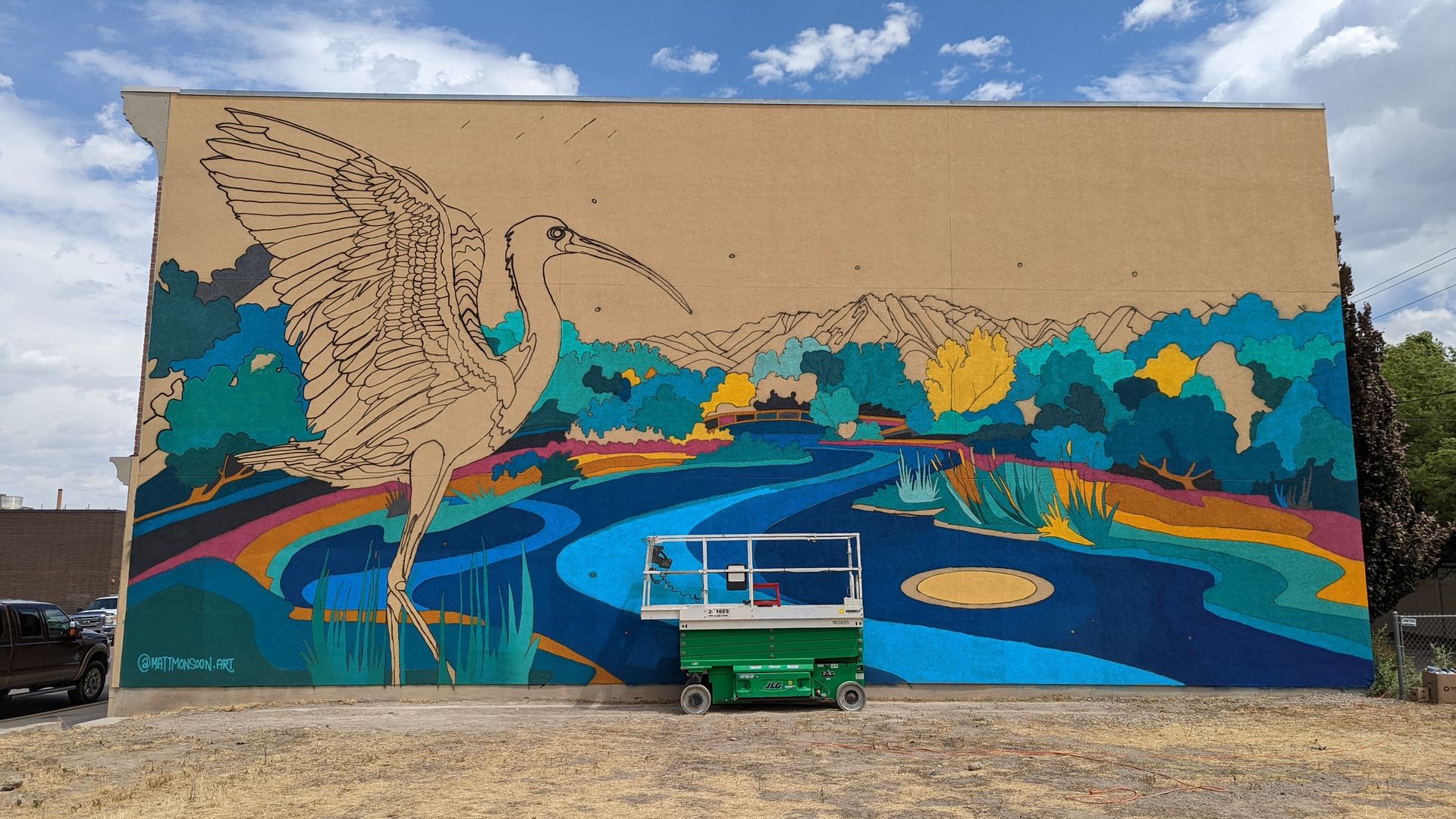 A mural is being painted on a building wall.
