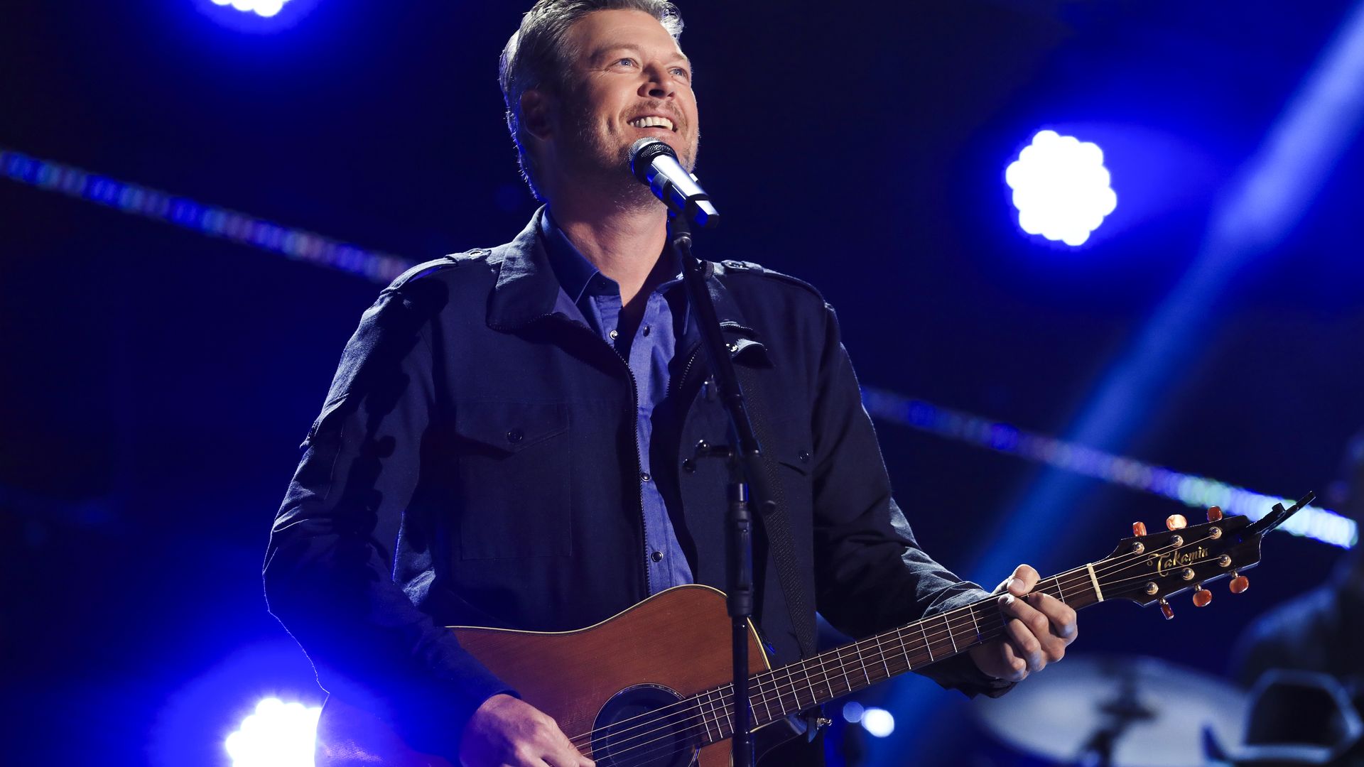 Country star Blake Shelton performing with a guitar and singing.