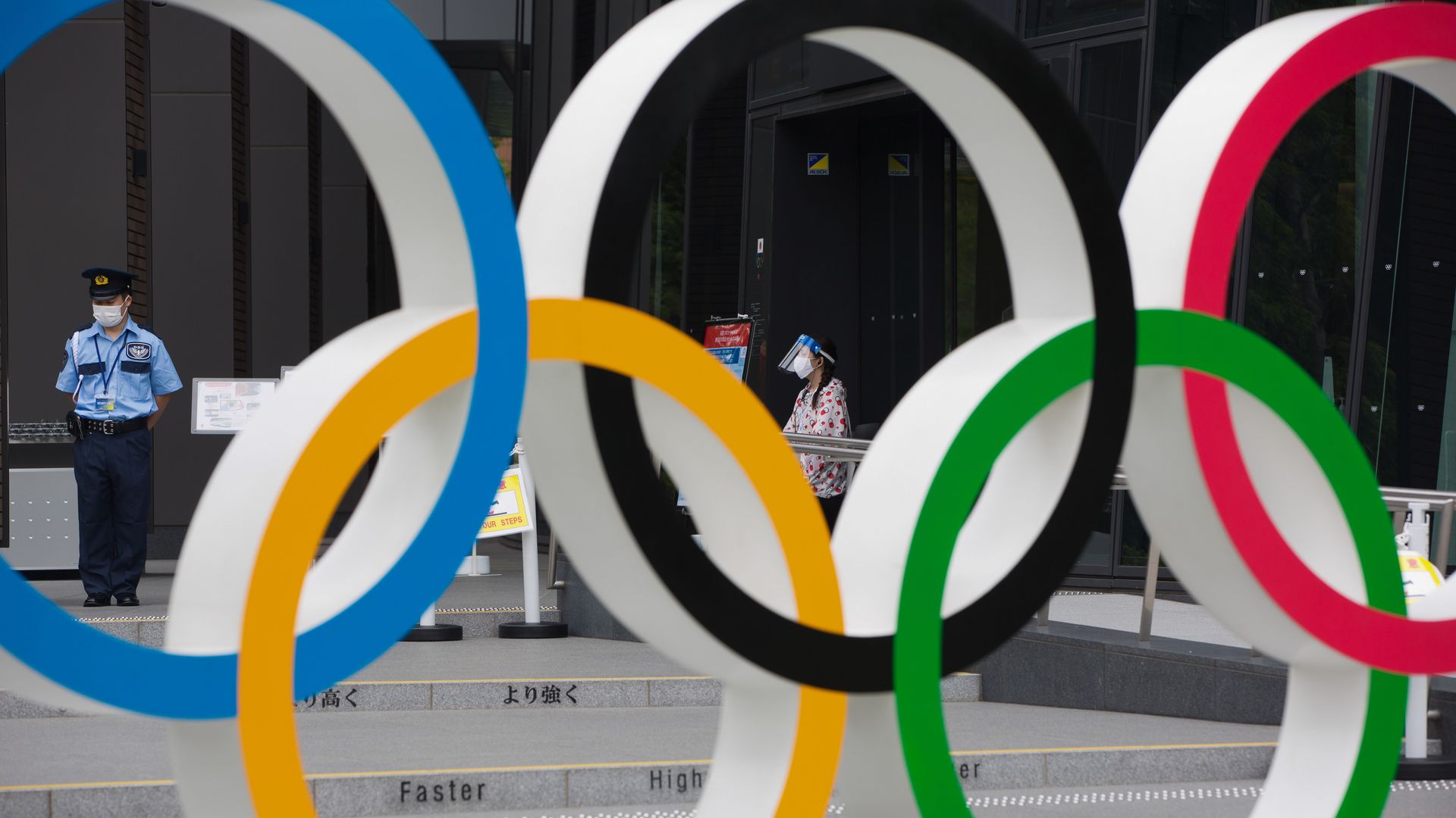 Photo of the Olympic rings monument and a masked security officer