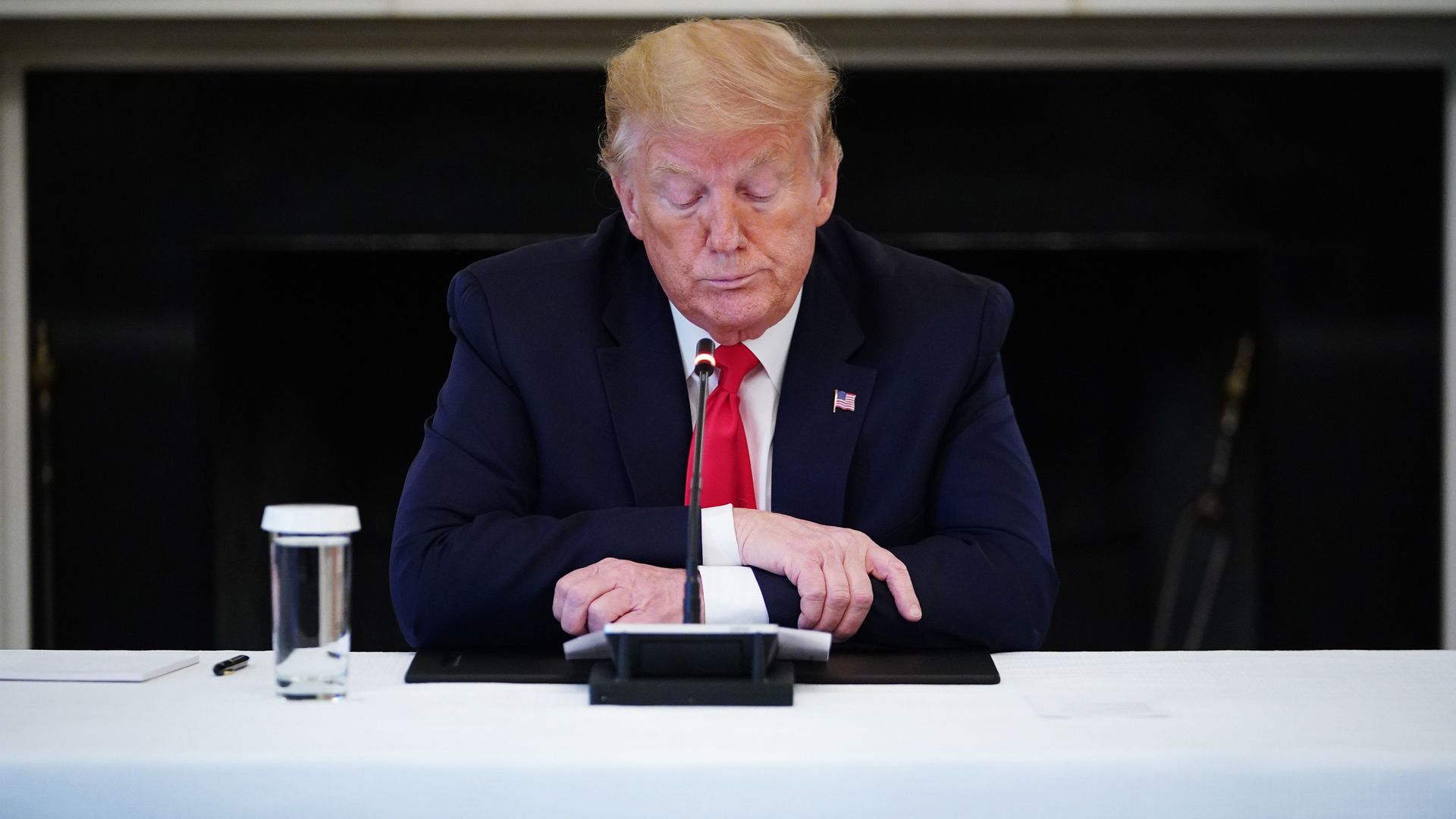 In this image, Trump sits at a table
