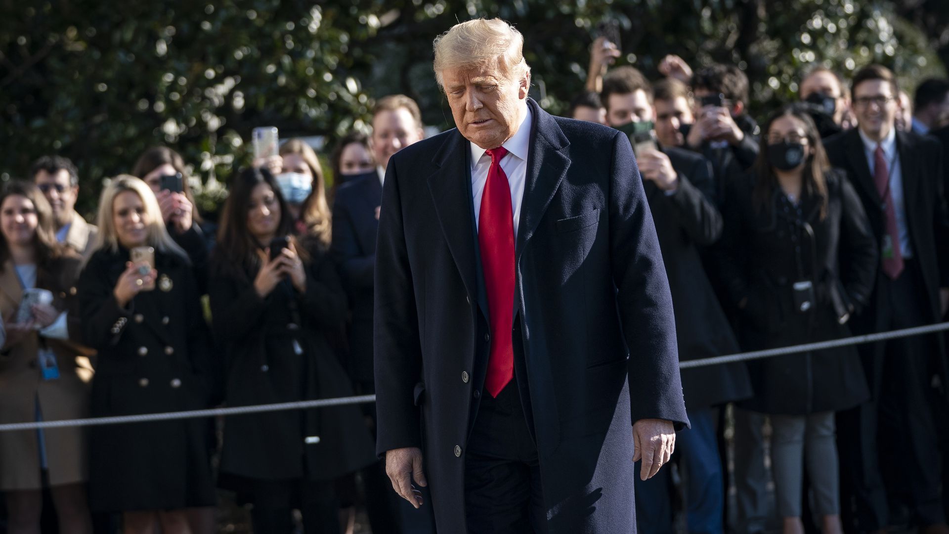 Trump walks, with his head slightly bowed, towards Marine One.