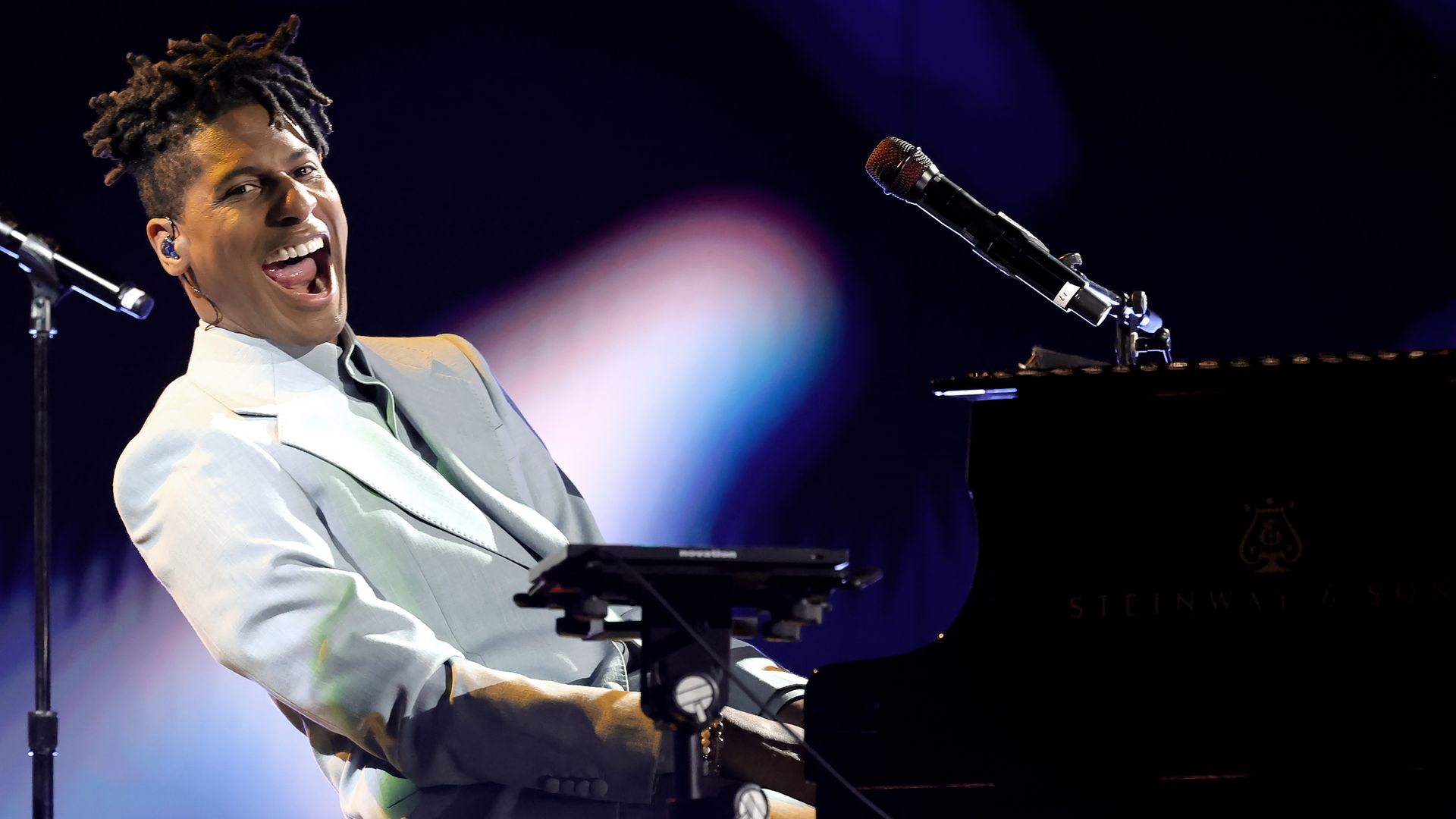 artist jon batiste plays piano while singing