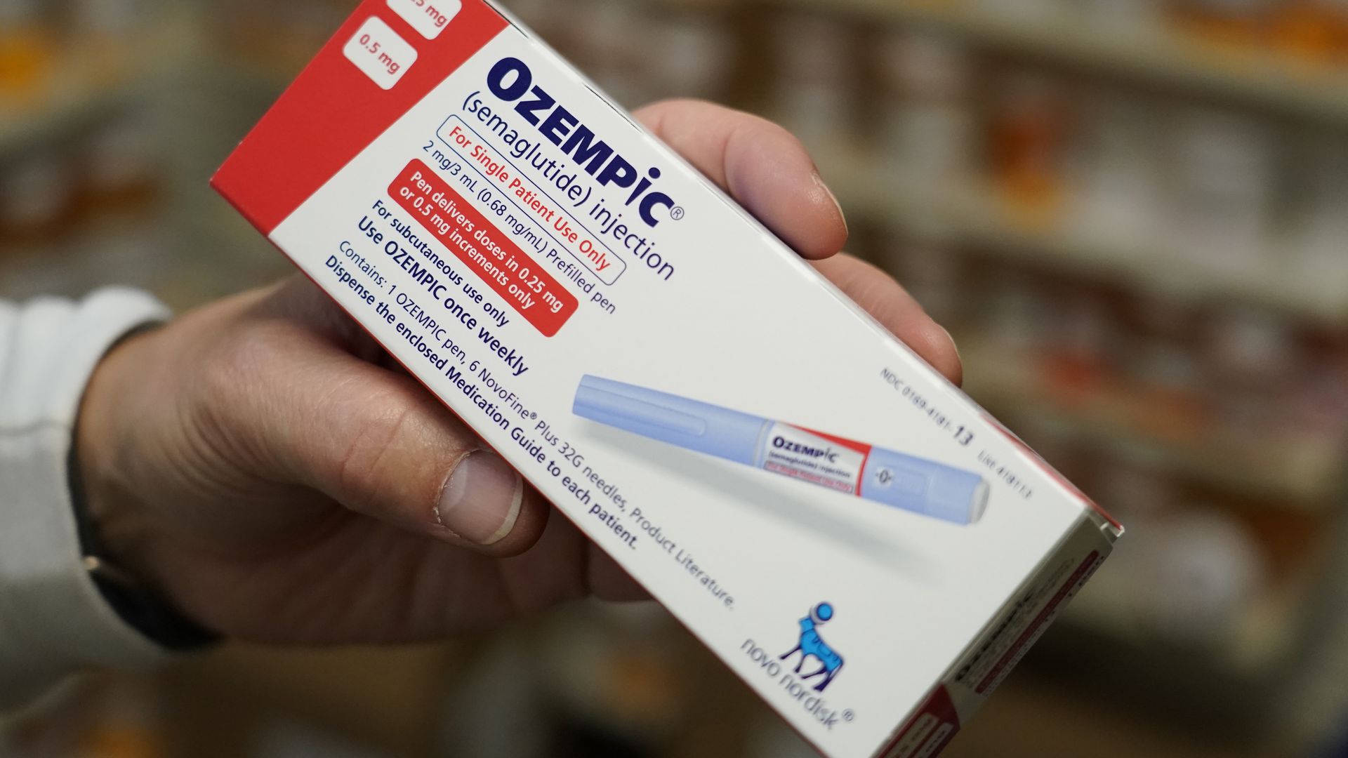 A close-up photo of pharmacist's hand holding an Ozempic box