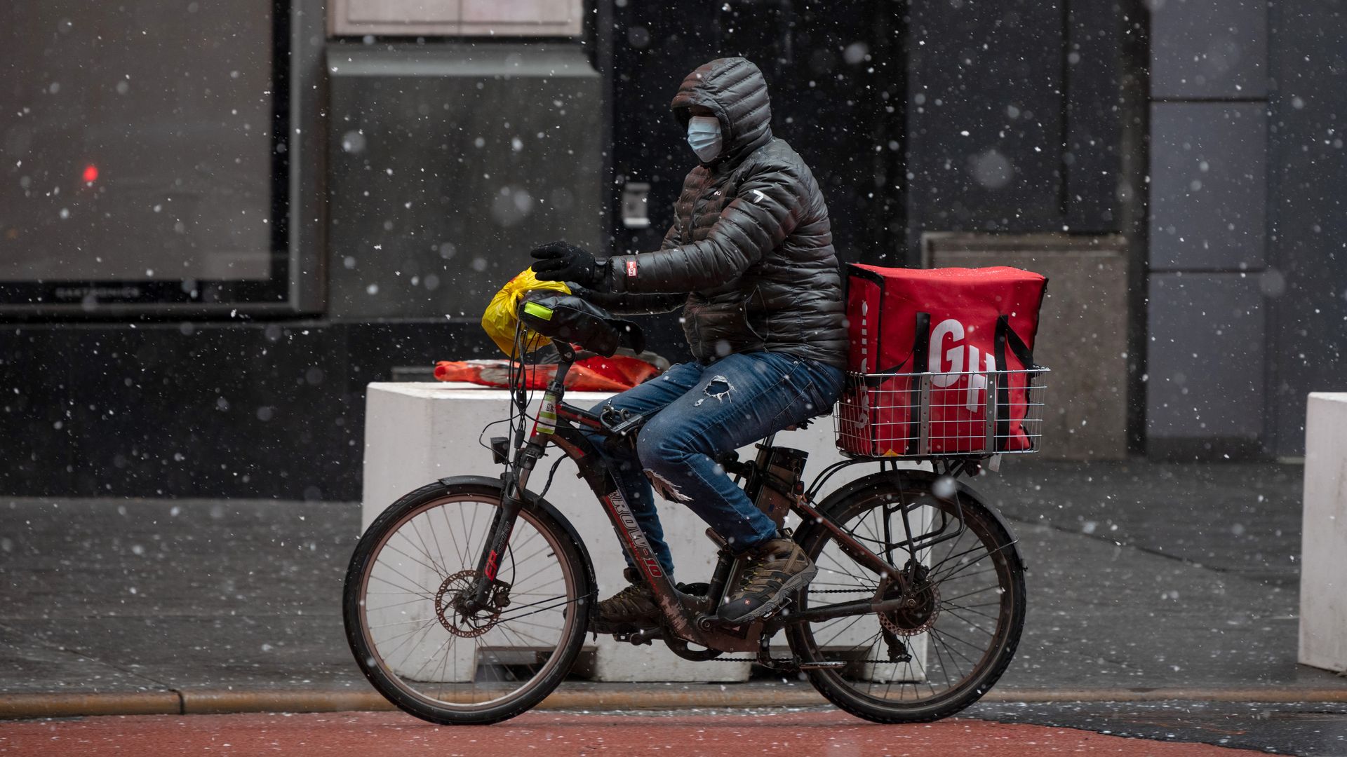 A Grubhub food delivery driver rides a bicycle during a snow storm 