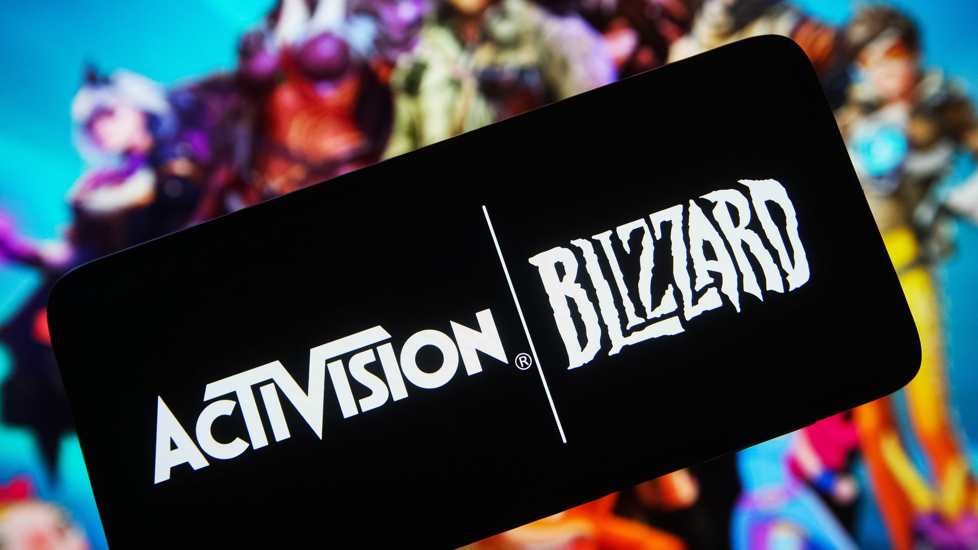 Photo illustration of Activision Blizzard logos on a phone, with colorful game characters behind them