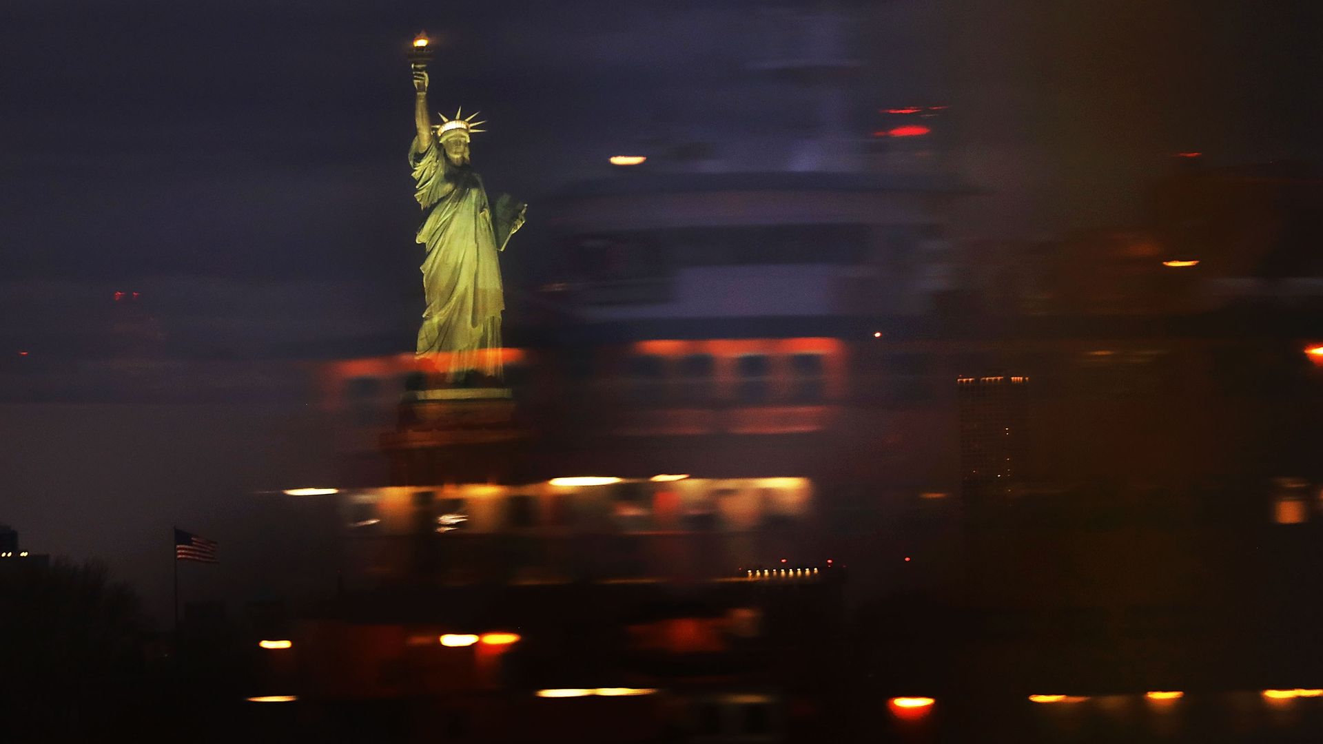 The Statue of Liberty seen through a blur of moving cars and lights