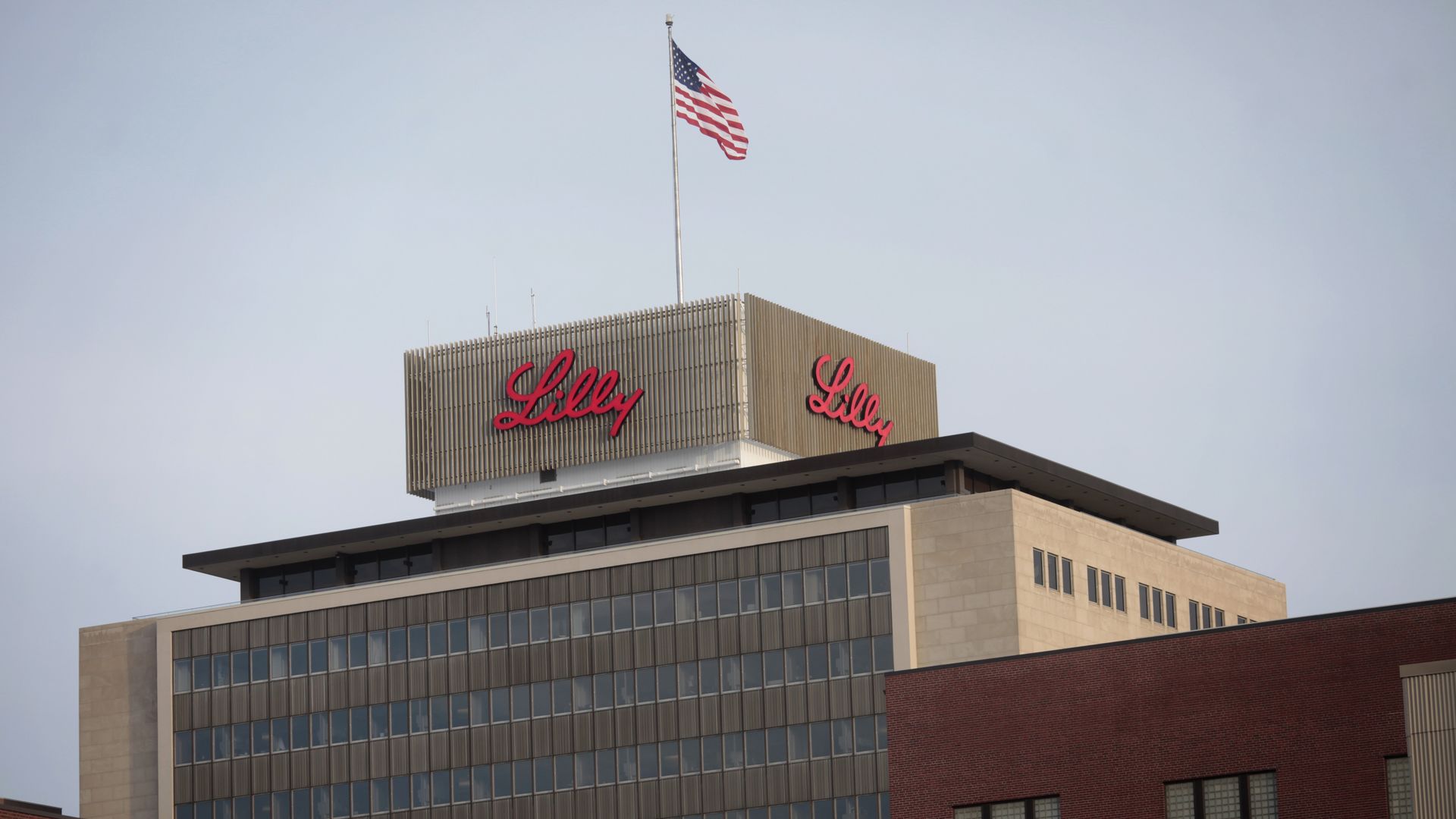 Eli Lilly corporate headquarters building with its red logo and an American flag.