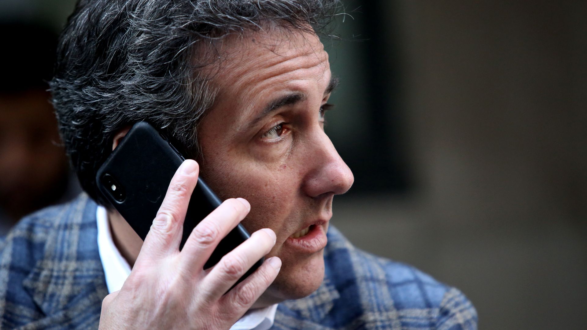 Michael Cohen holding a phone to his ear. 