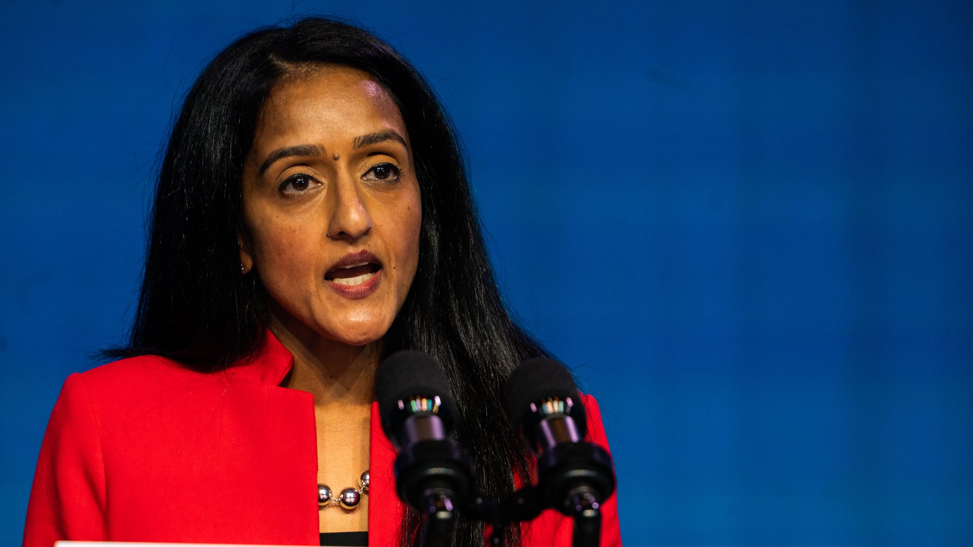 Vanita Gupta speaks standing behind podium