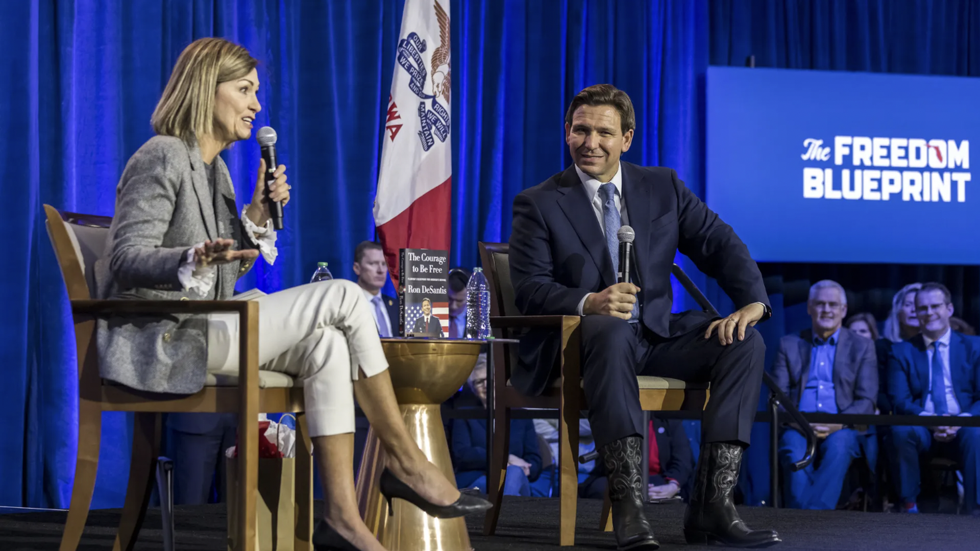 Kim Reynolds speaking into mic with Ron DeSantis