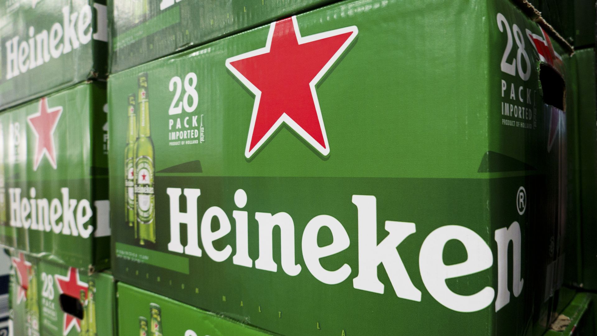 Stacked green boxes of Heineken beer, each labeled with a large red star, "Heineken" in white text, and "28 pack imported product of Holland".