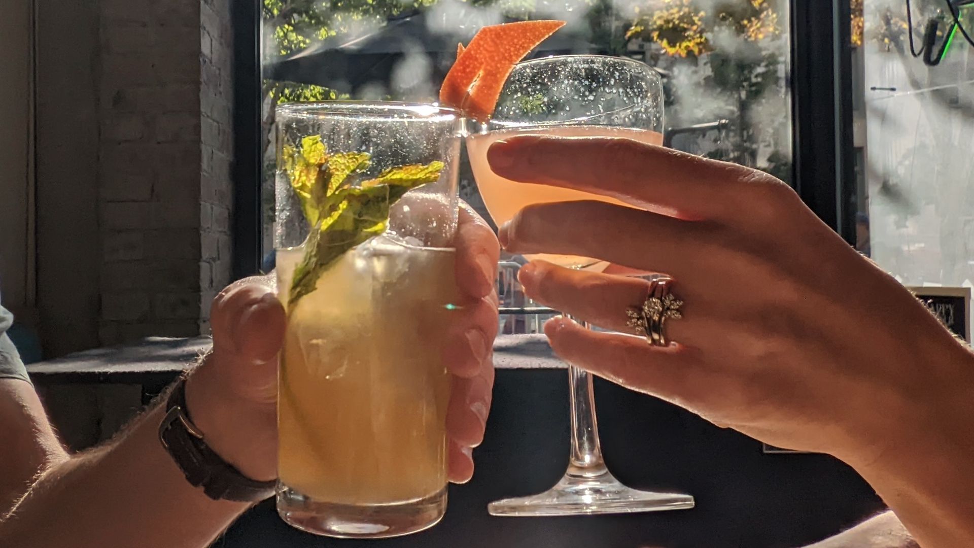 Two cocktail glasses clink in a toast.