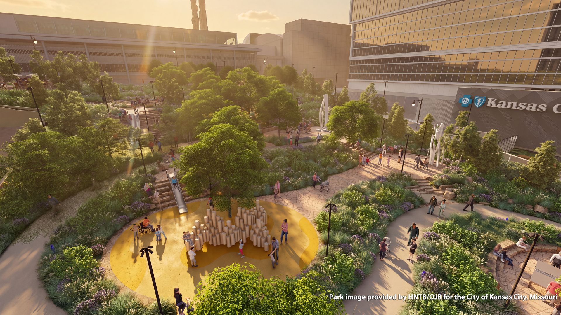 Sunlit urban park between glass office buildings; green trees, winding paths, and people strolling. A yellow circular plaza with wooden column sculpture; Kansas City sign visible.