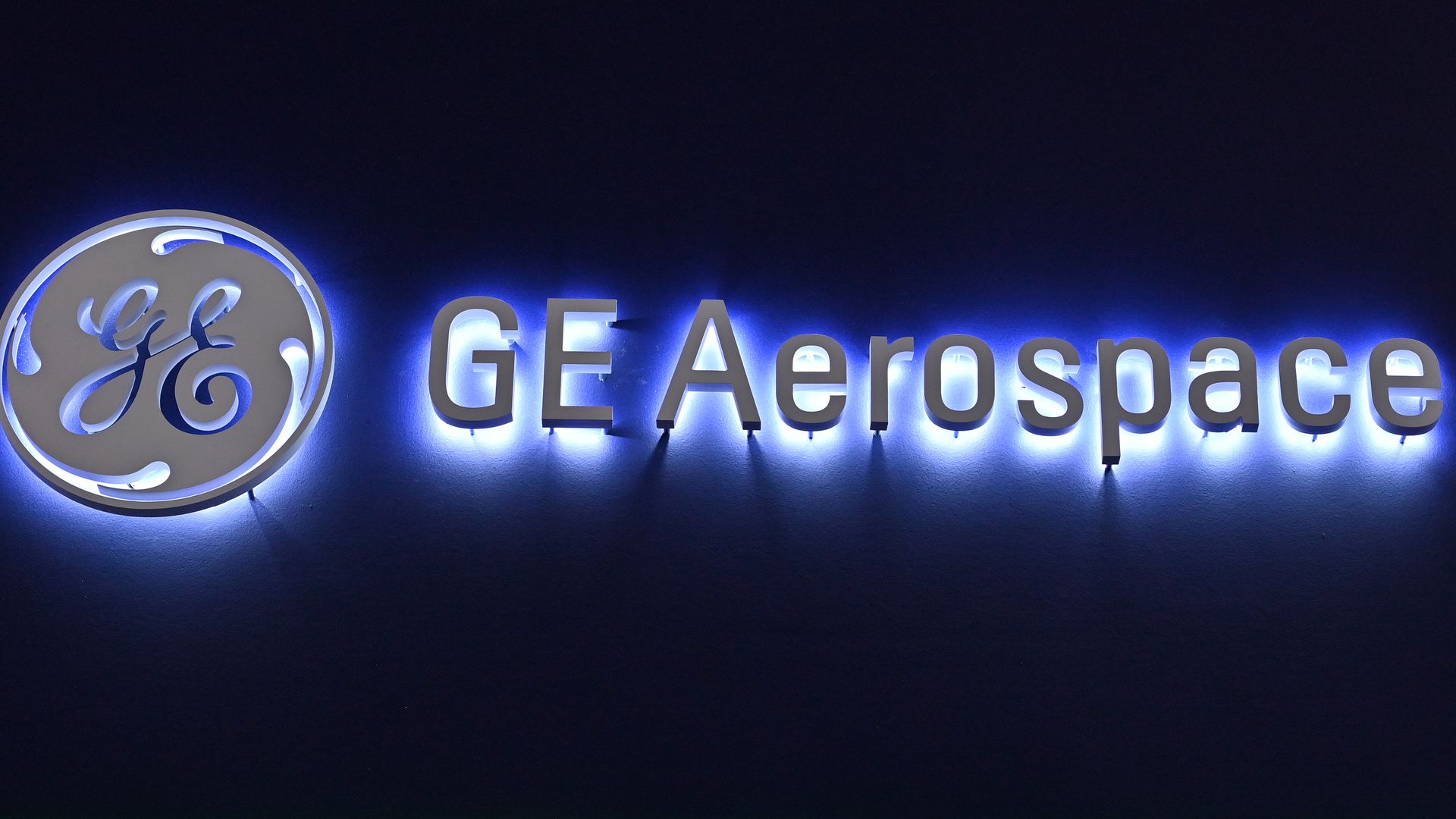 A backlit GE logo and the words "GE Aerospace" are shown on a black background. 