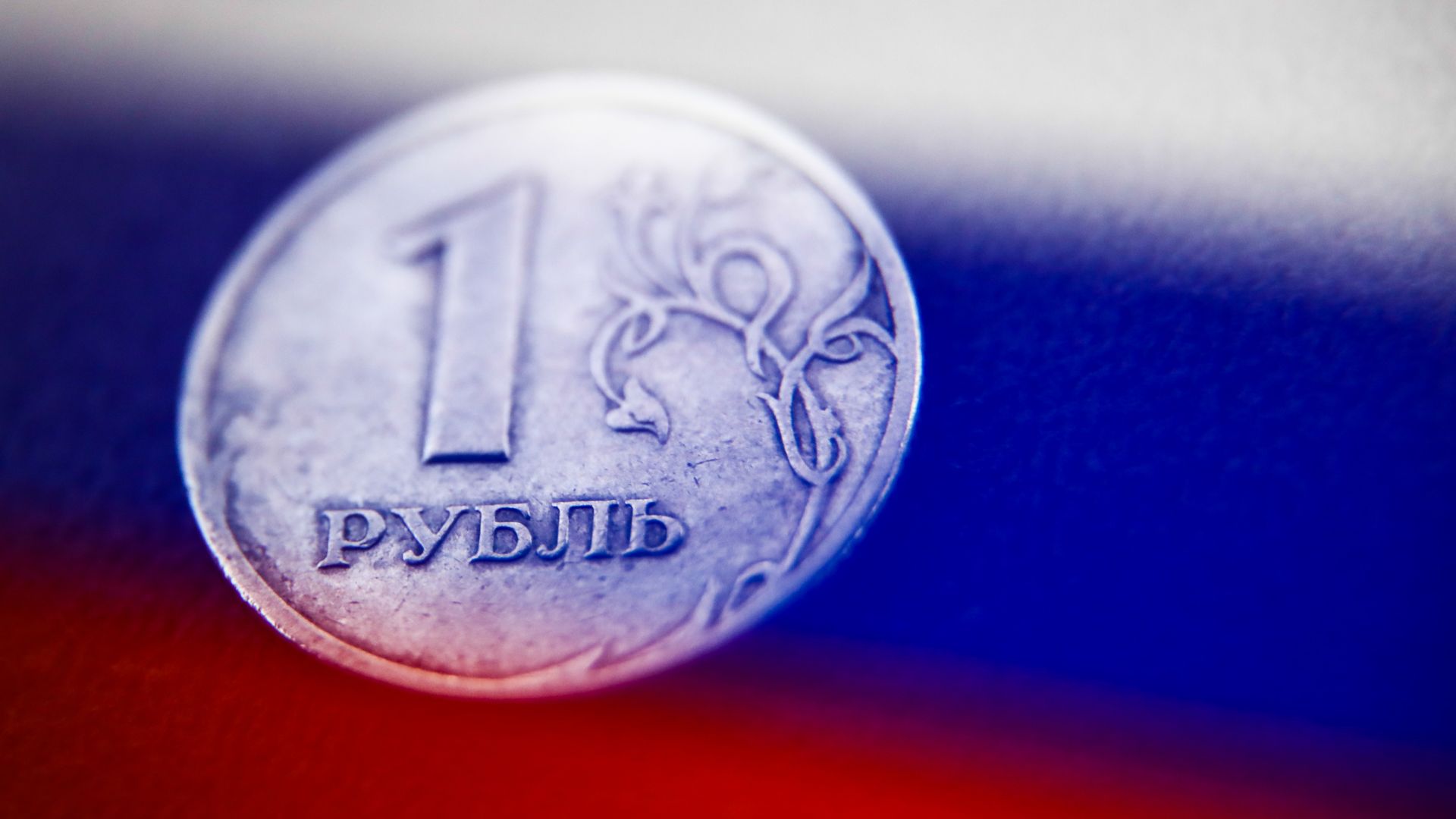Russian ruble coin against the Russian flag