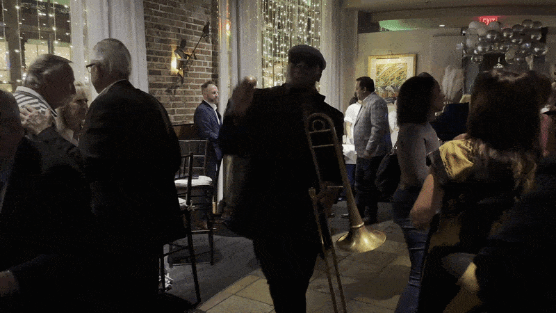 Image shows a man with a horn dancing in a crowd.