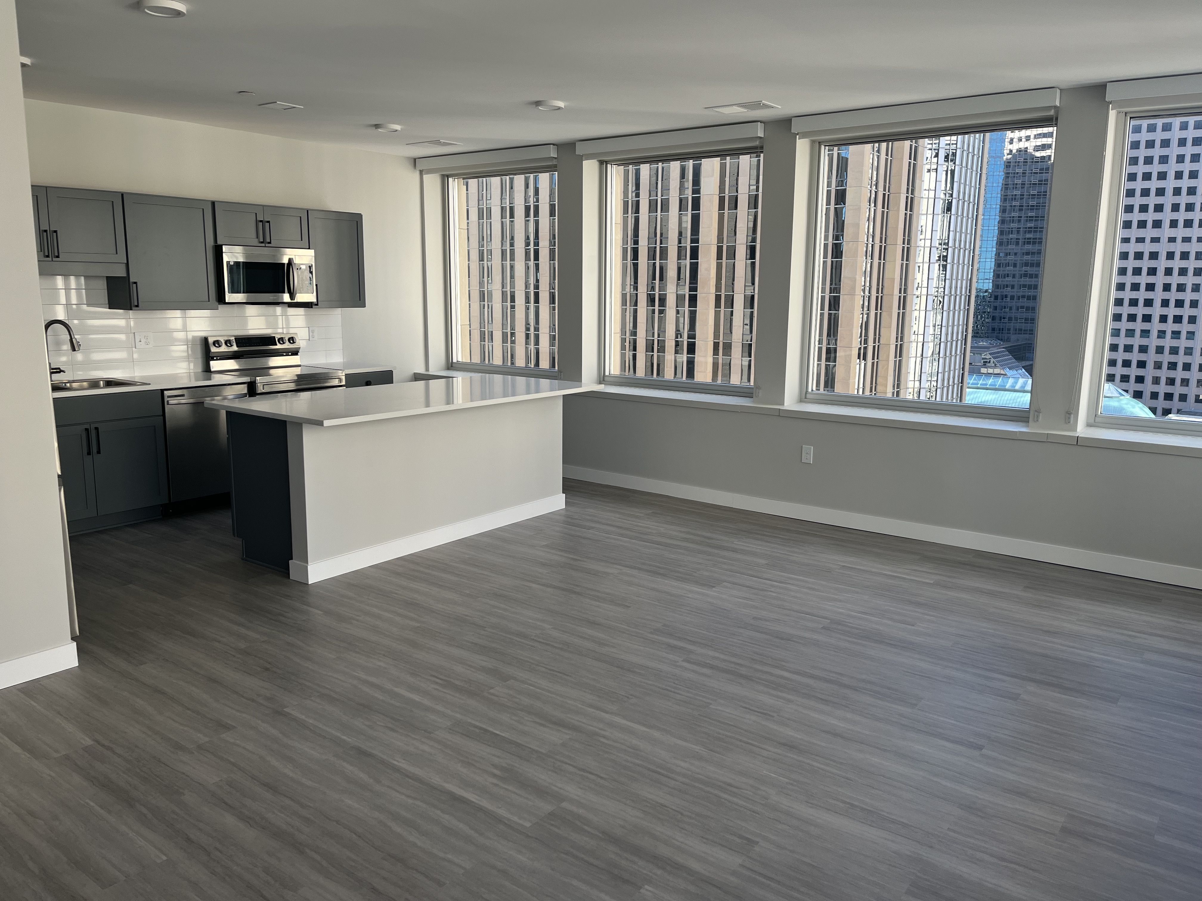 A photo of a kitchen and living room in an apartment with large windows 