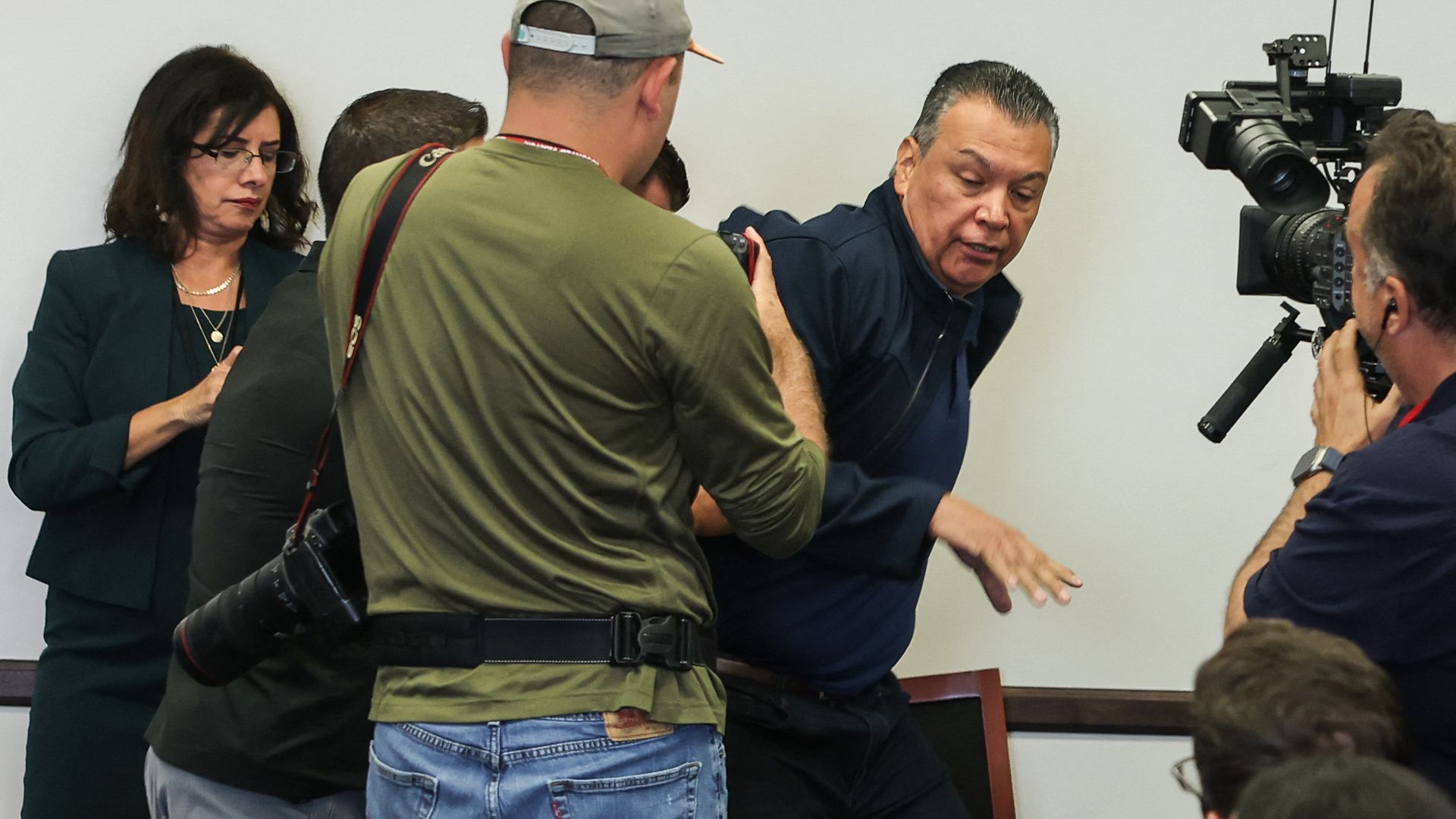 Senator Alex Padilla being forcibly removed by federal agents while camera crews take photos