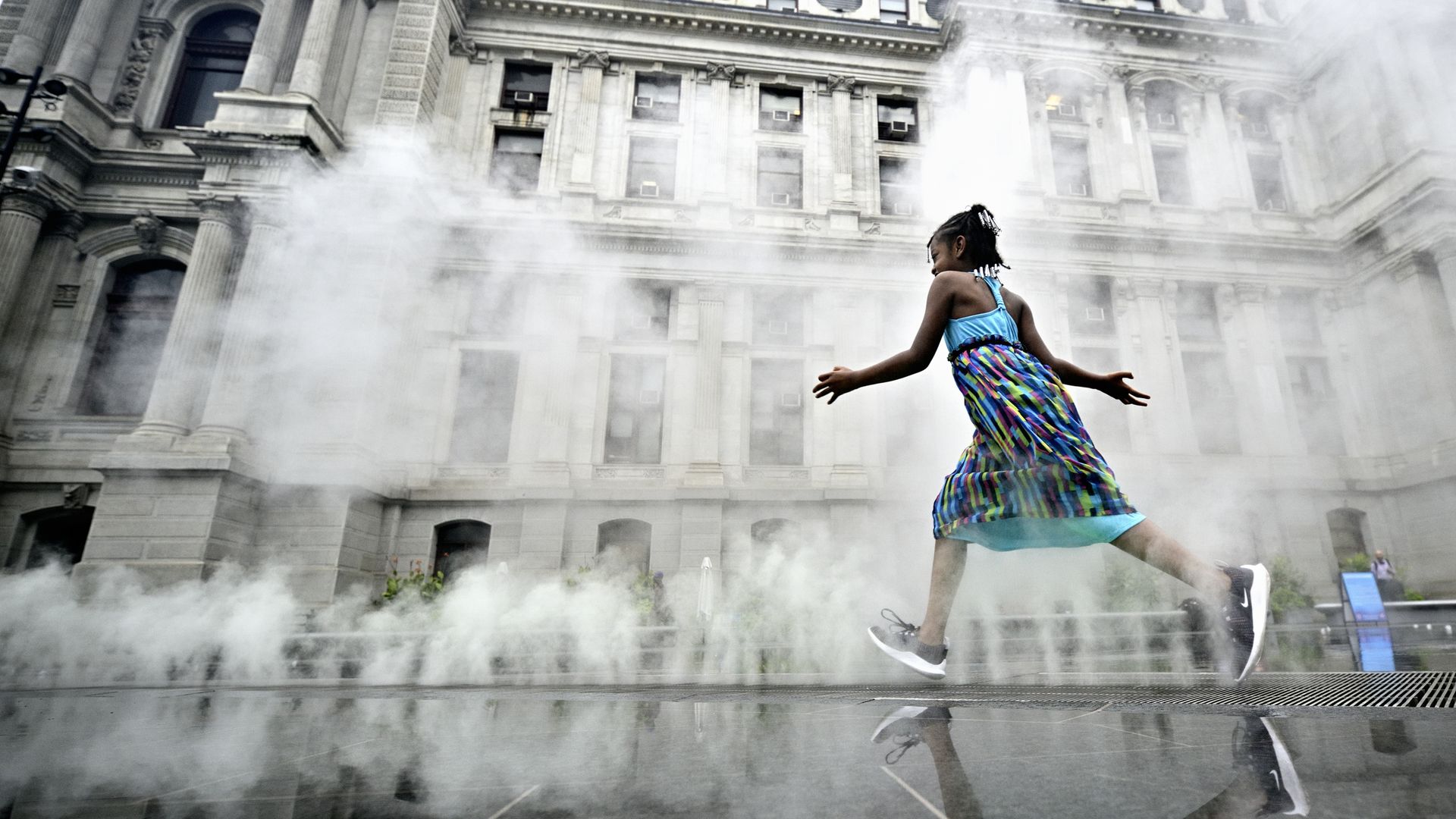 A young girl running through a splash ground in Philadelphia