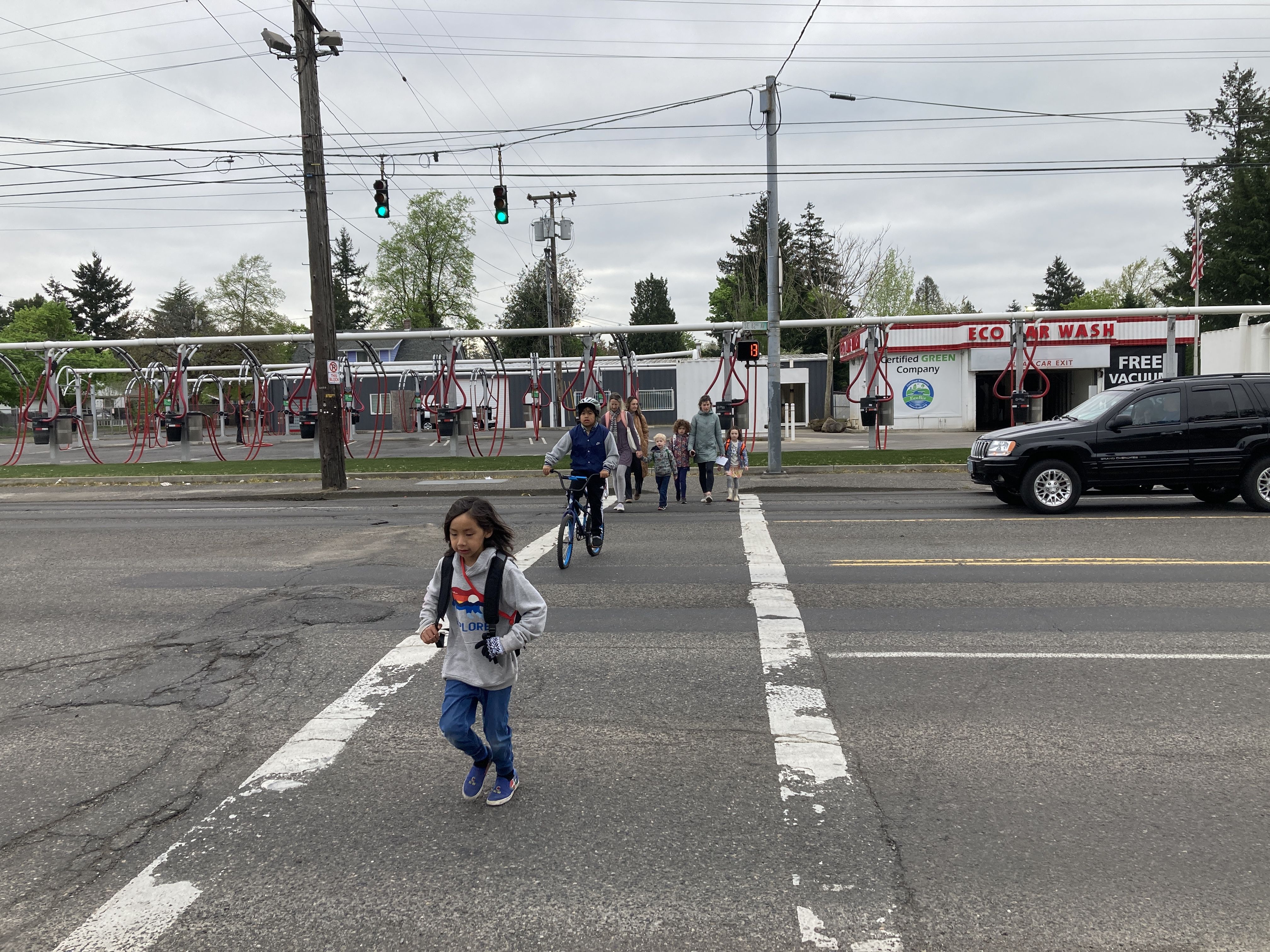 Children run across a four lane road in a crosswalk.