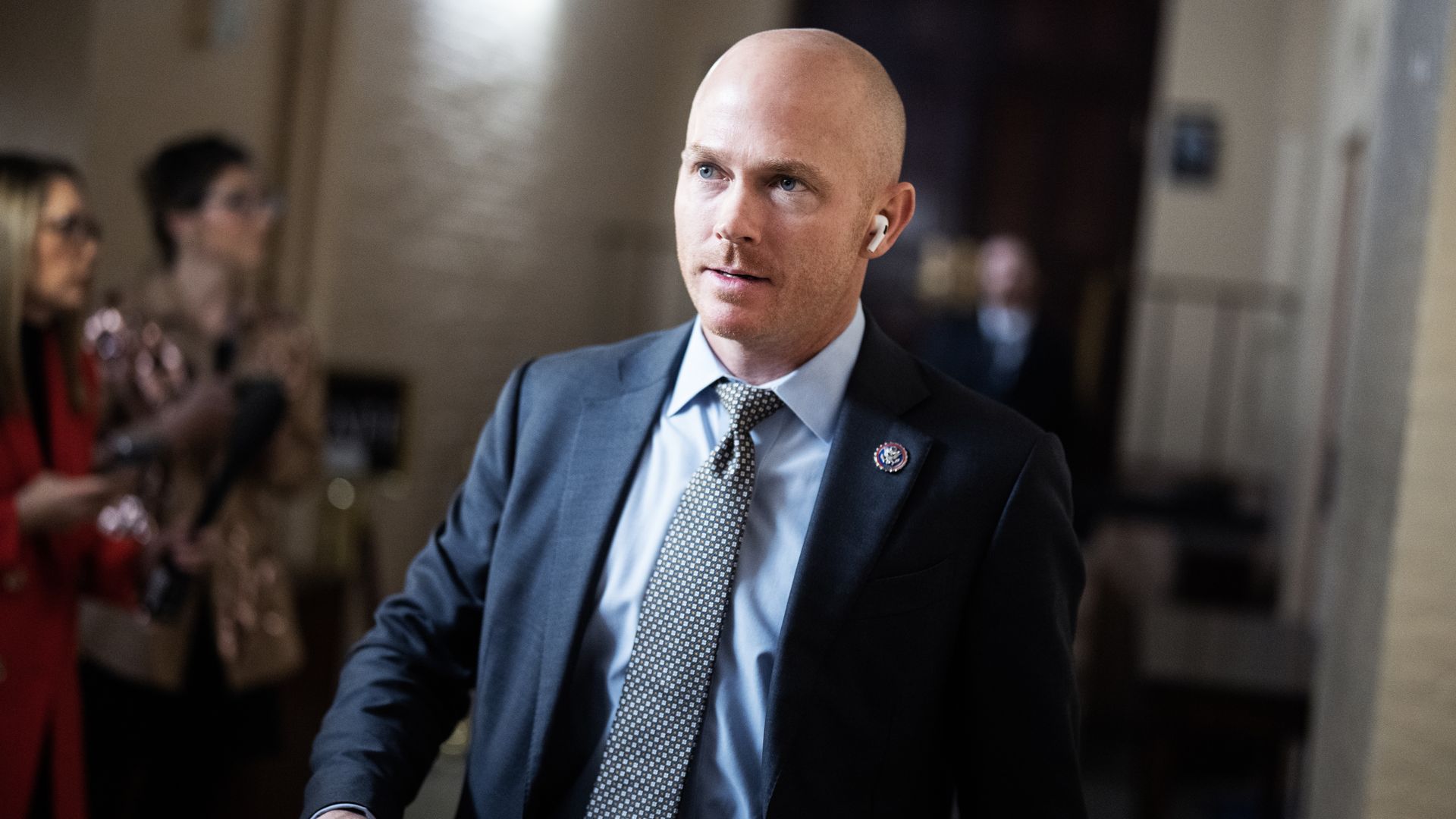 Rep. William Timmons, wearing a blue suit with an airpod in his ear, walking in the Capitol basement.