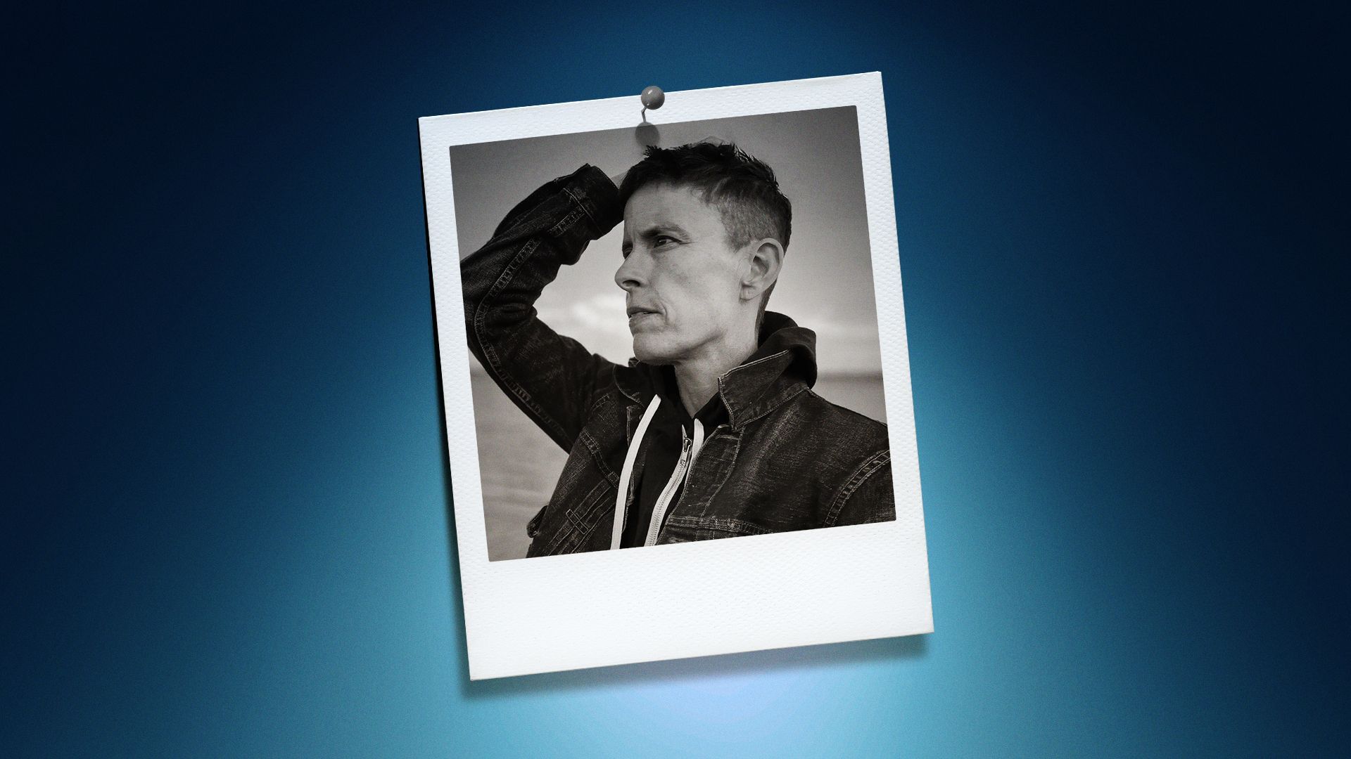 Photo illustration of Andrea Gibson in the center of a Polaroid photo under a blue spotlight.