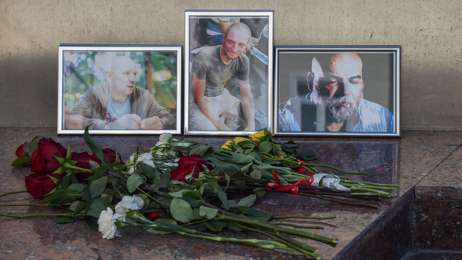 Flowers left in front of photos of three Russian journalists