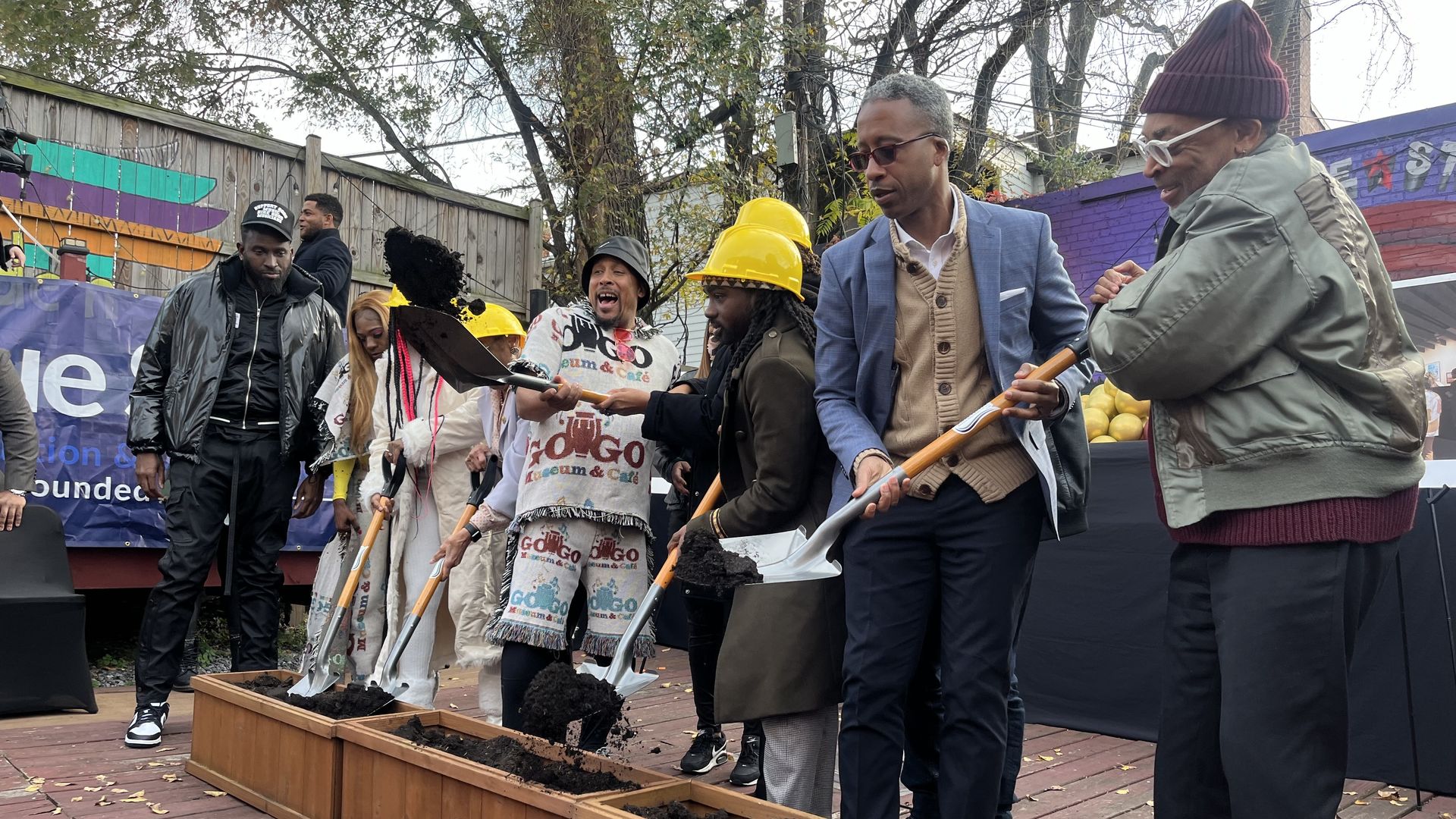 A group of people, including Spike Lee, dig shovels into planters full of soil.