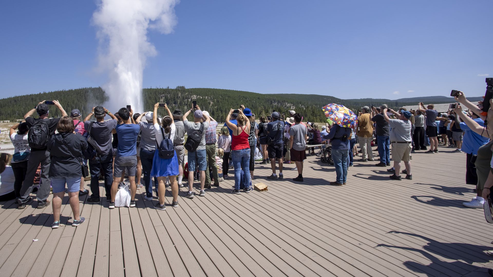 Hundreds of tourists gather on a boardwalk to watch Old Faithful Geyser erupt on on July 14, 2021 at Yellowstone National Park, Wyoming. (Natalie Behring/Getty Images)