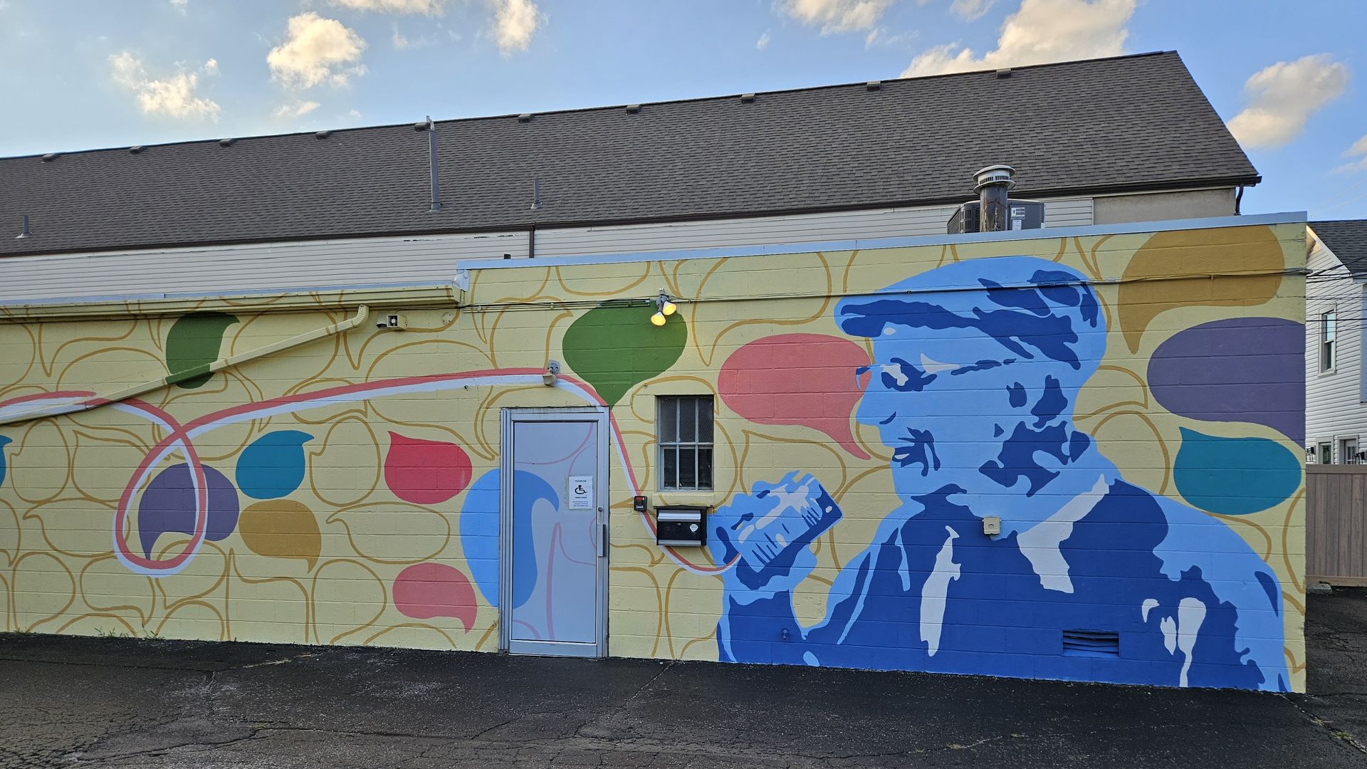 A colorful mural depicting a man speaking into a tin can