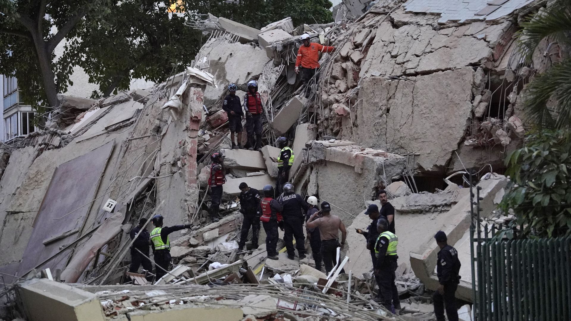 A collapsed building with workers trying to dig in the rubble. 