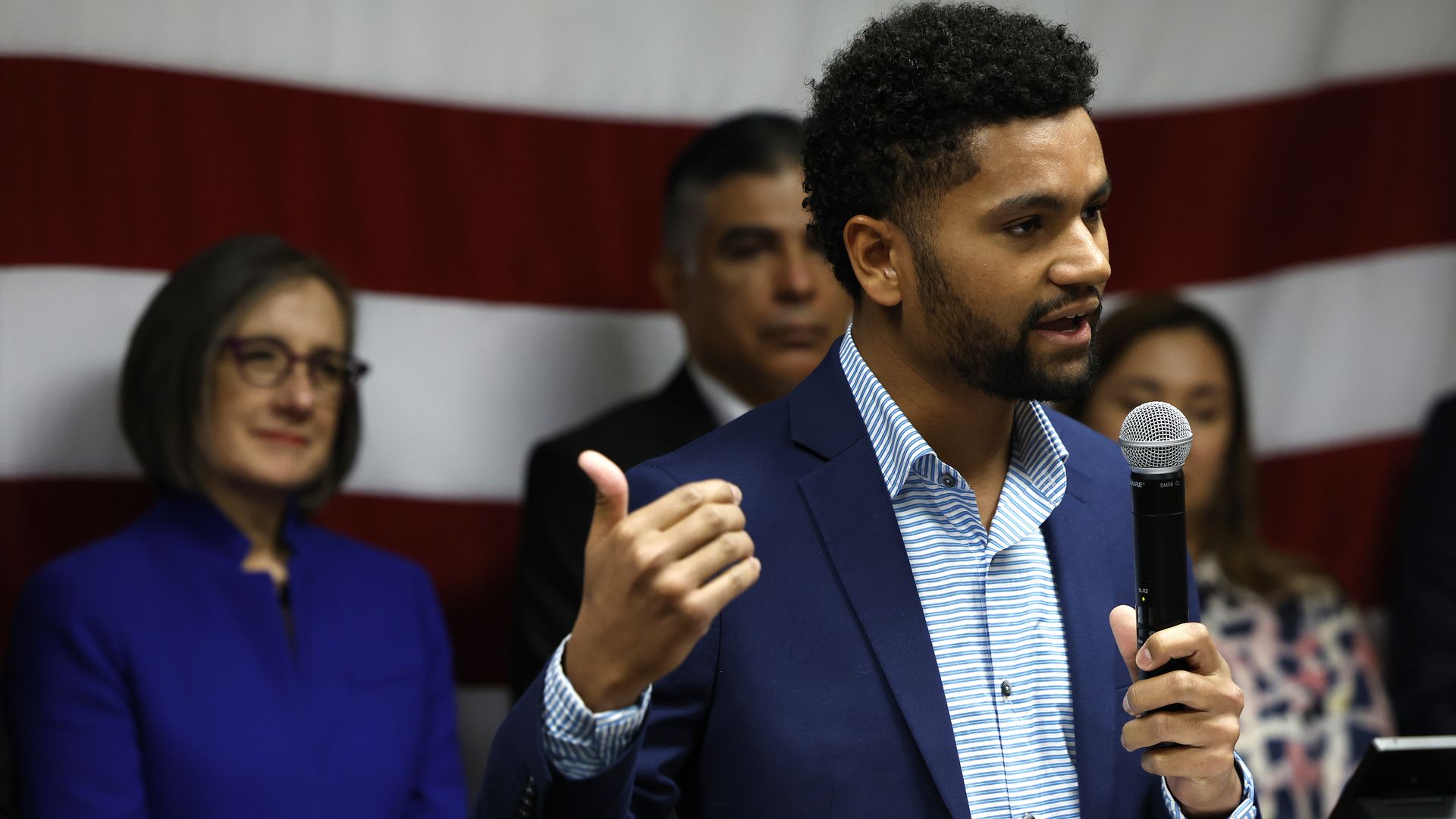 Congressman-elect Maxwell Frost of Florida standing at a podium holding a microphone in his left hand while talking
