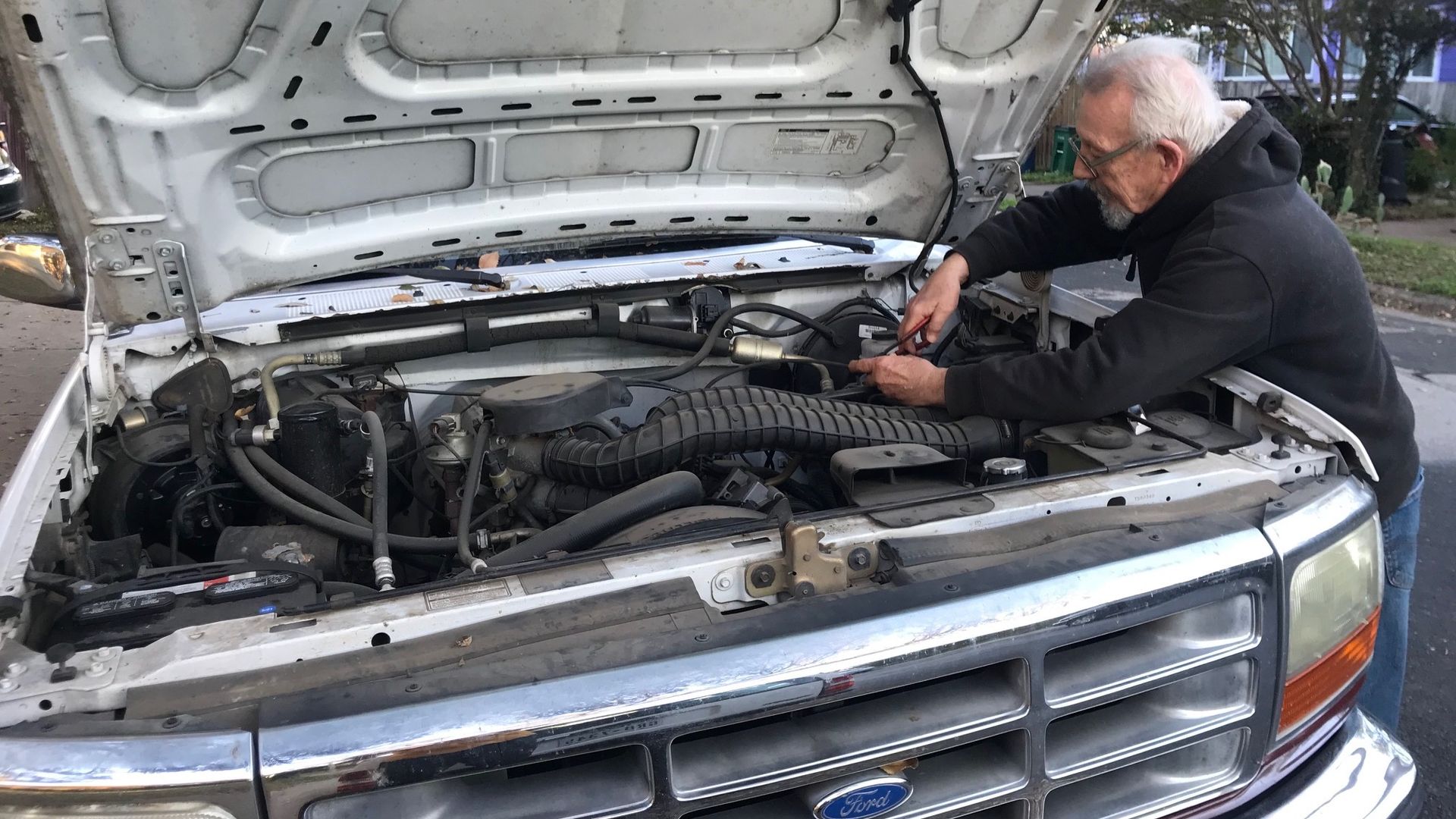 Asher's neighbor Gary examines his truck's engine.