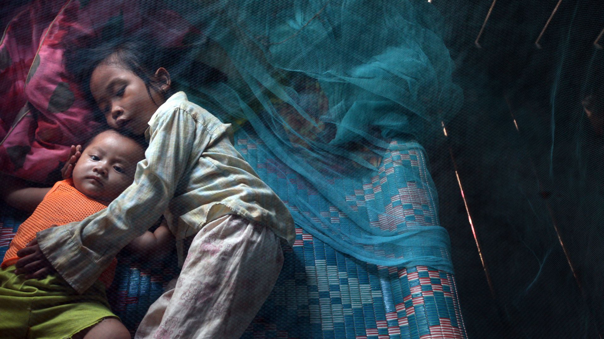 Kids underneat a mosquito net