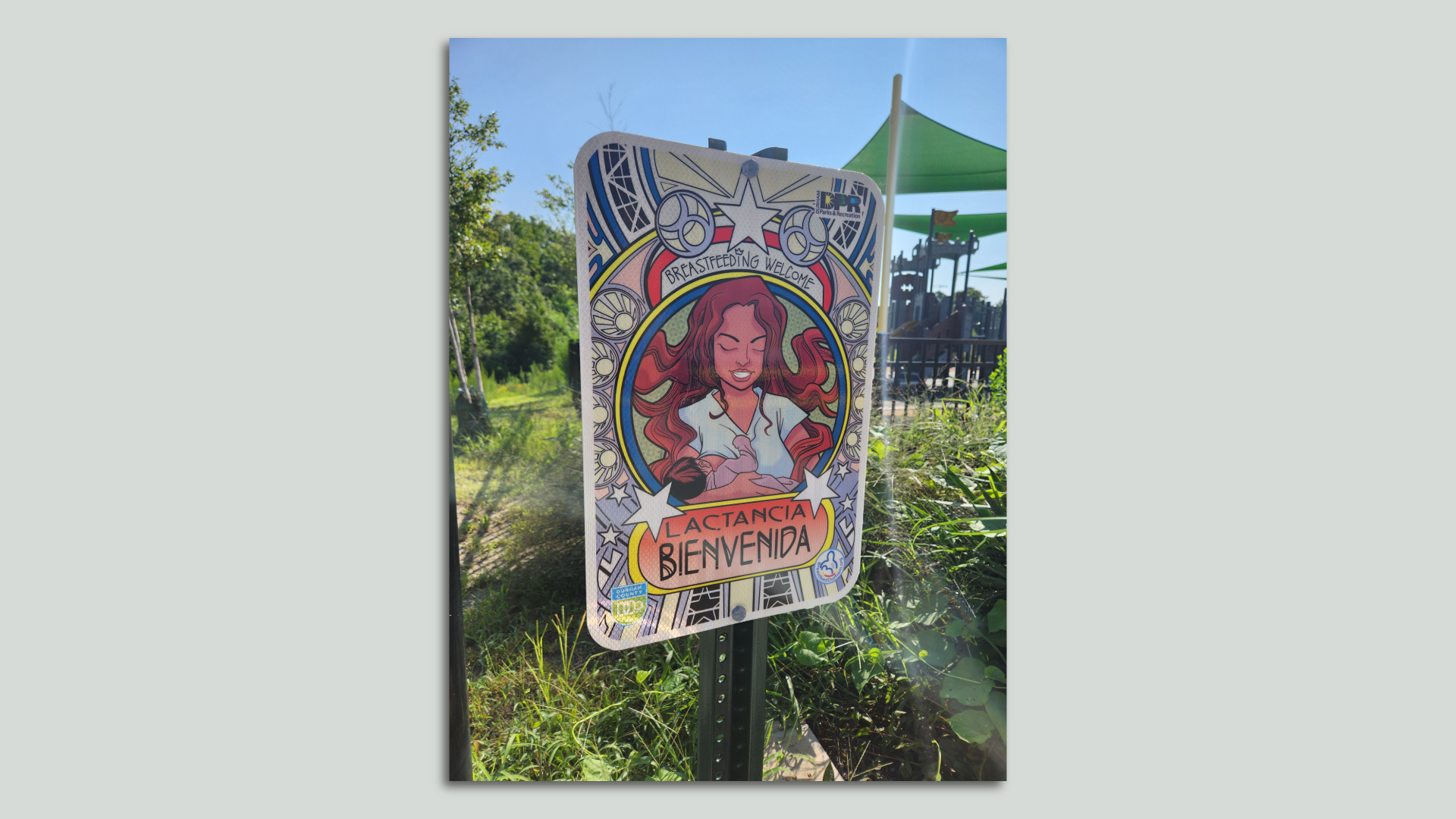 A photo of a sign in a Durham Park that reads "Lactancia Bienvenida," which means "Breastfeeding Welcome"