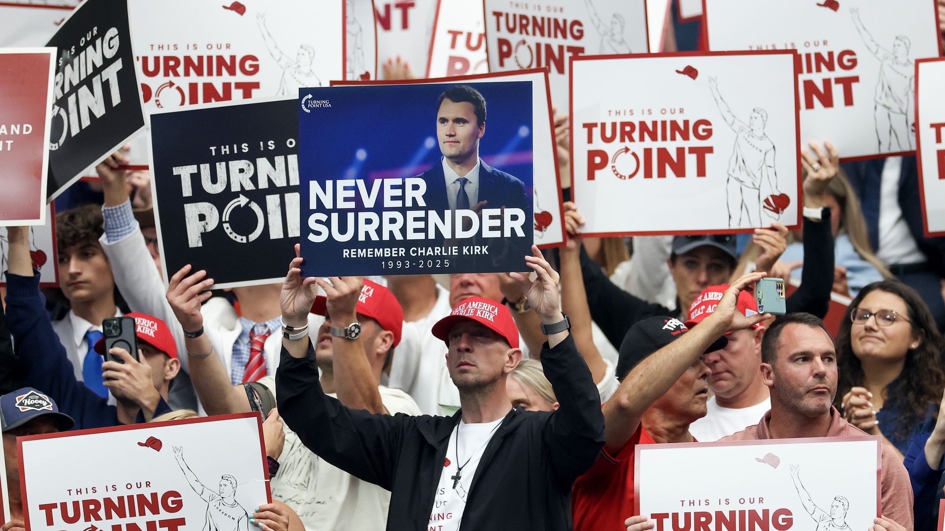 Attendees hold up signs at the memorial service for political activist Charlie Kirk at State Farm Stadium on September 21, 2025 in Glendale, Arizona.