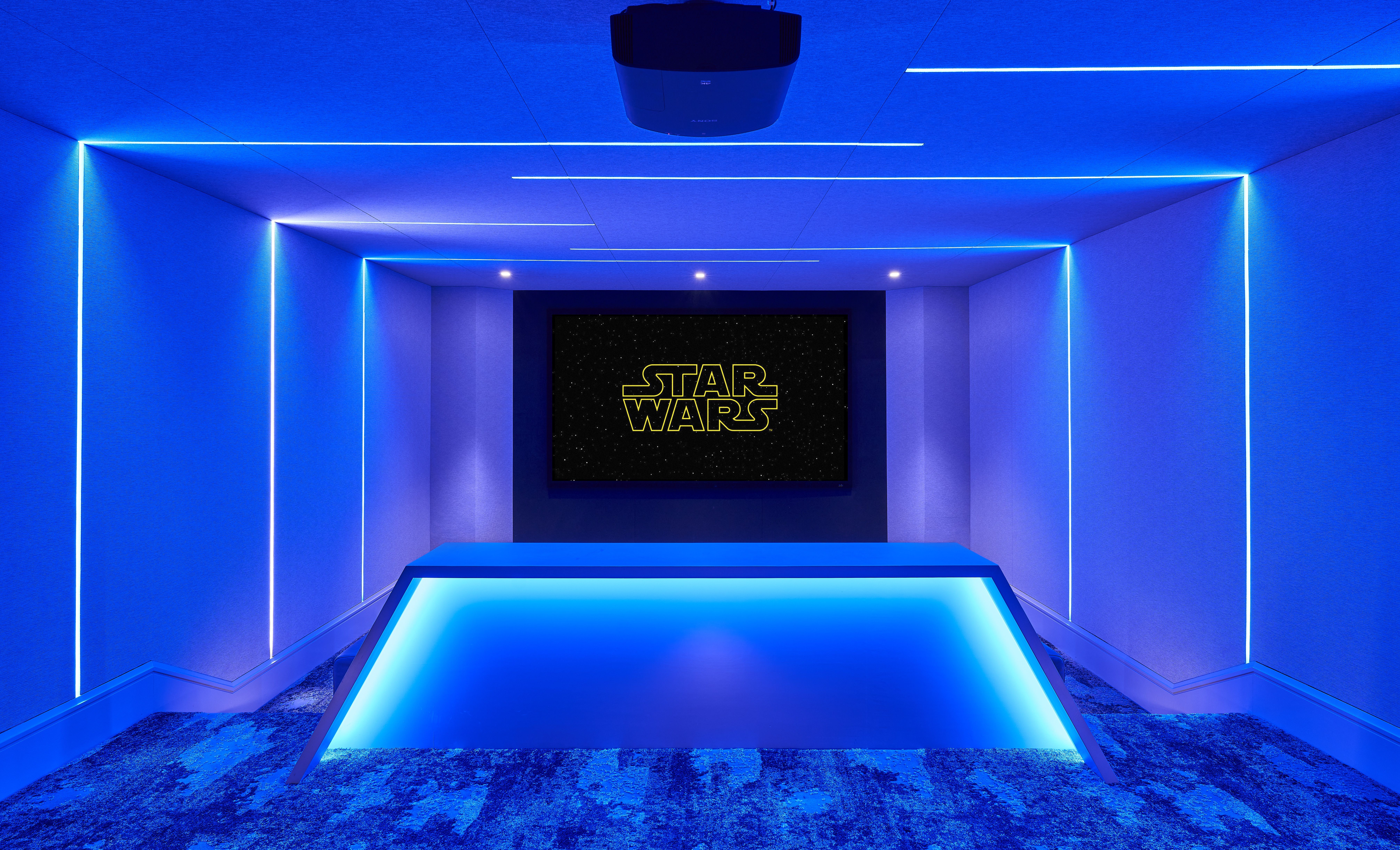 Blue neon-lit hallway with glowing edges and a blue platform foreground; at the far end, a screen displays the yellow "STAR WARS" logo on a starry background.