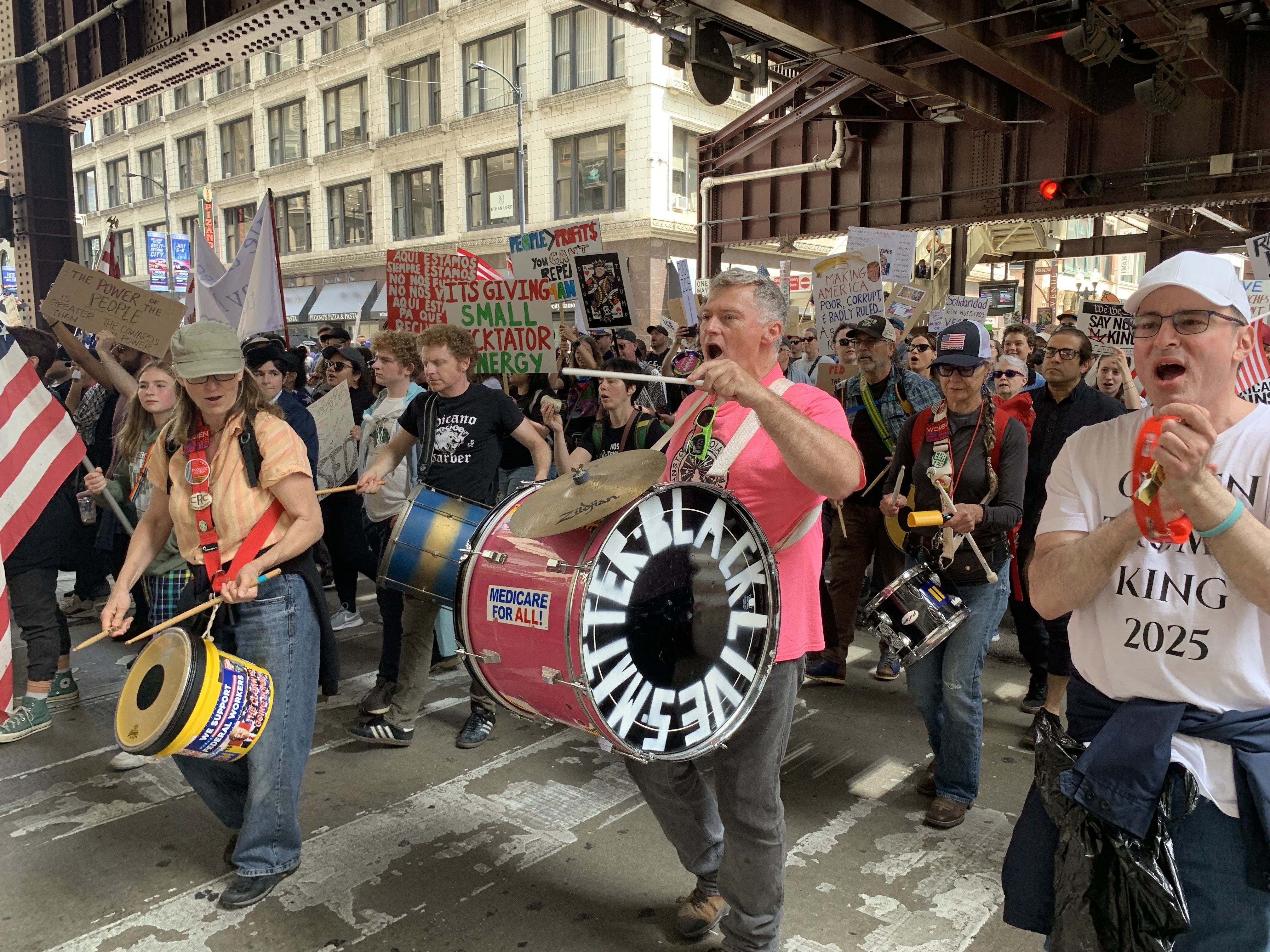Protesters fill up a plaza with signs and march on a street. 