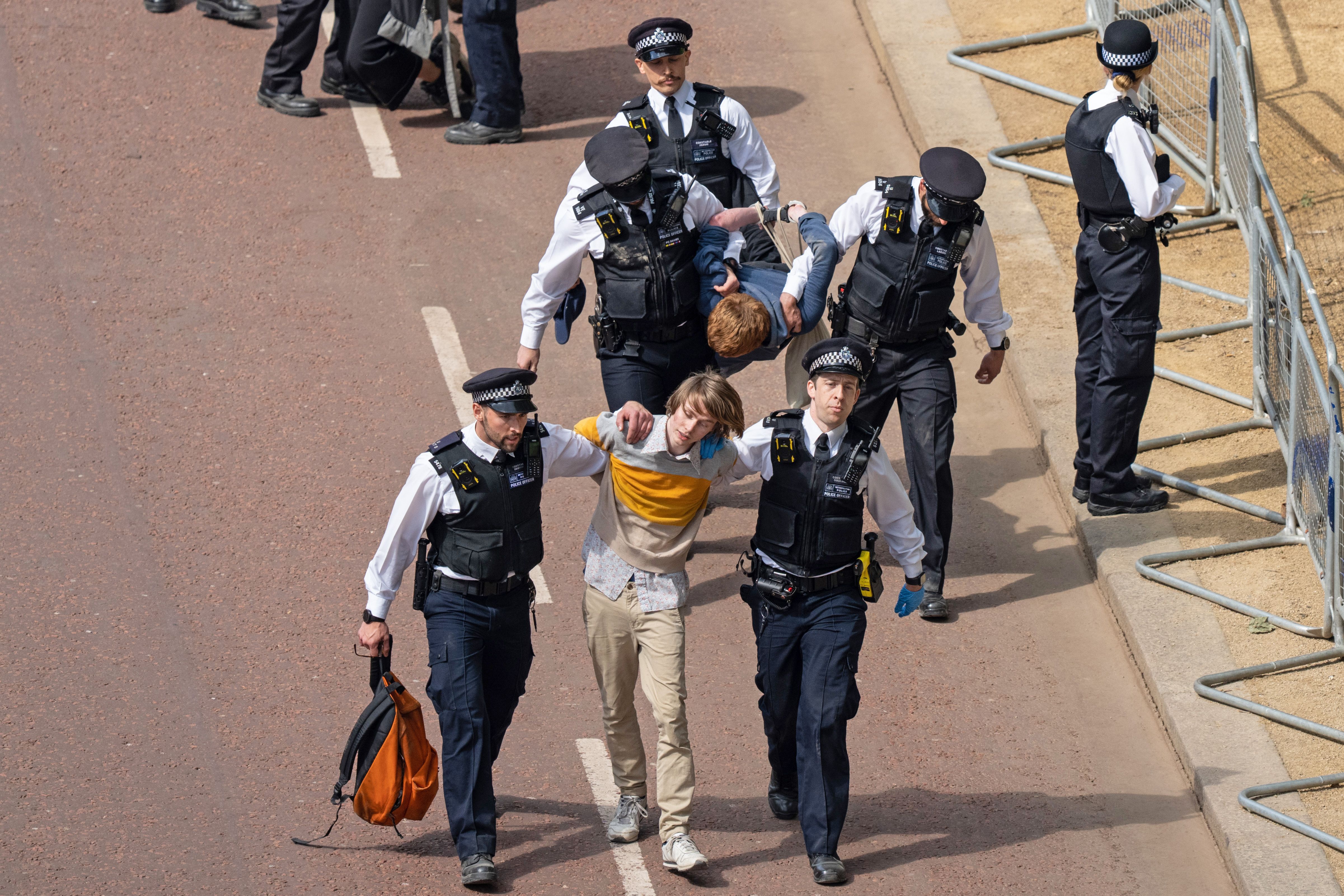 Police officers remove people who ran into the path of the royal procession 
