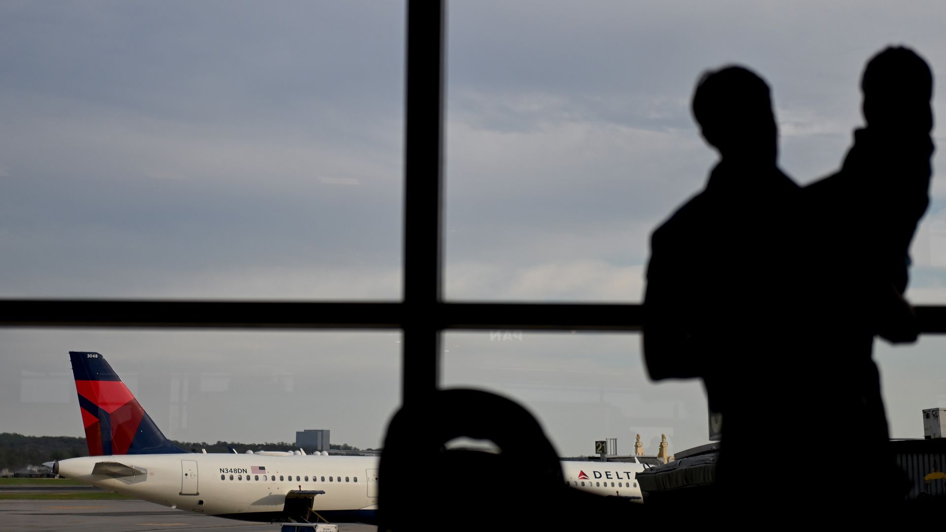 Silhouettes of father and daughter standing at an airport window