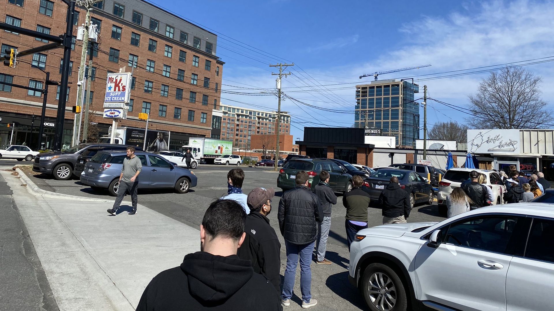 a line of people in the parking lot of Mr. K's burger joint. A squat building on the right is the 53-year-old Mr. K's. A tall brick building across the street is a new shopping center.