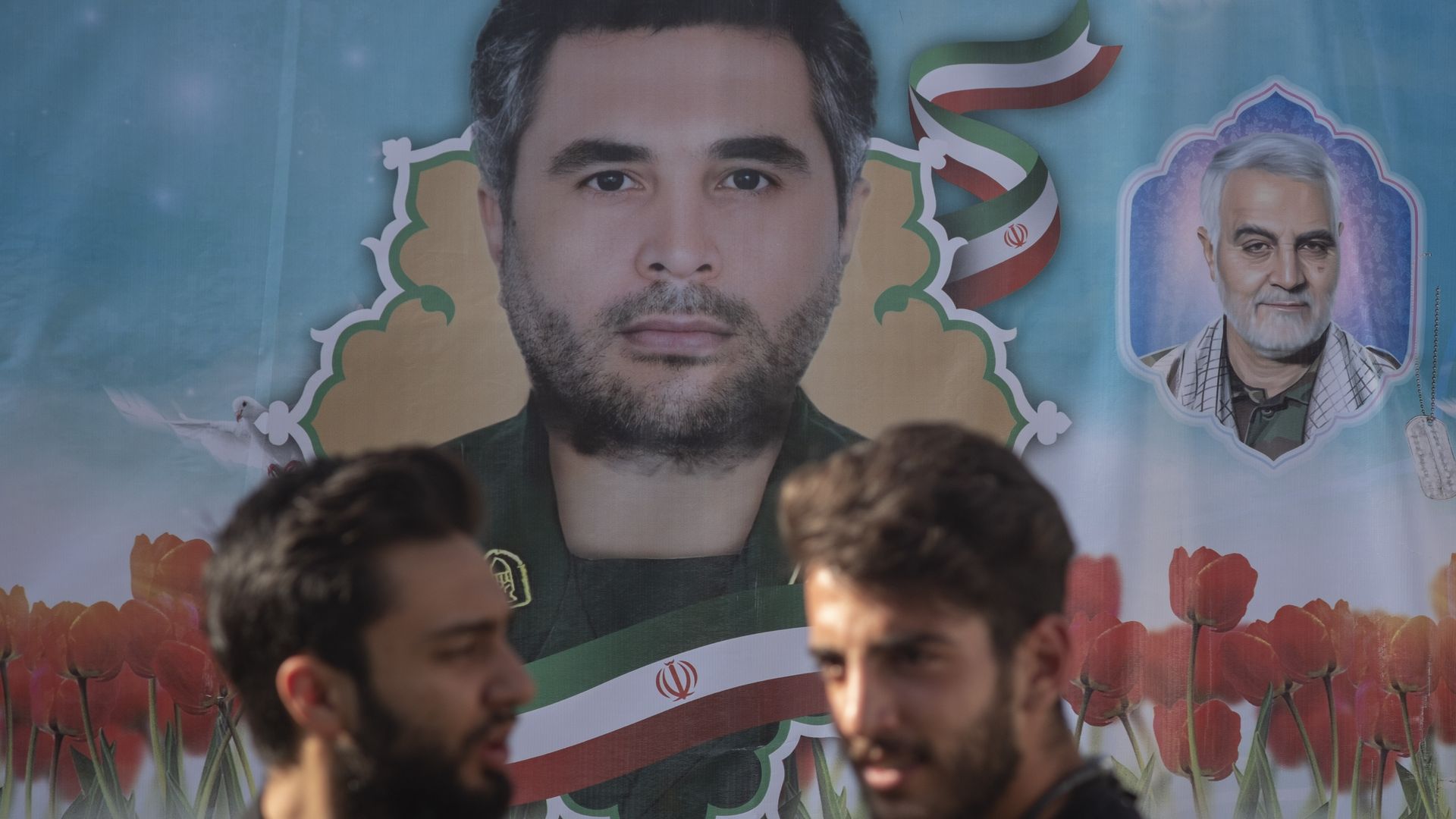 stand under a portraits of the assassinated Islamic Revolutionary Guard Corps Commander, Colonel Sayyad Khodai, and the former Commander of IRGCs Quds Force, General Qasem Soleimani during a rall