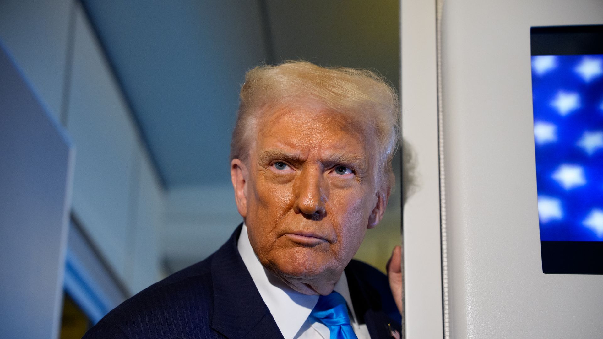 Trump wearing a navy suit jacket, white shirt and blue tie 